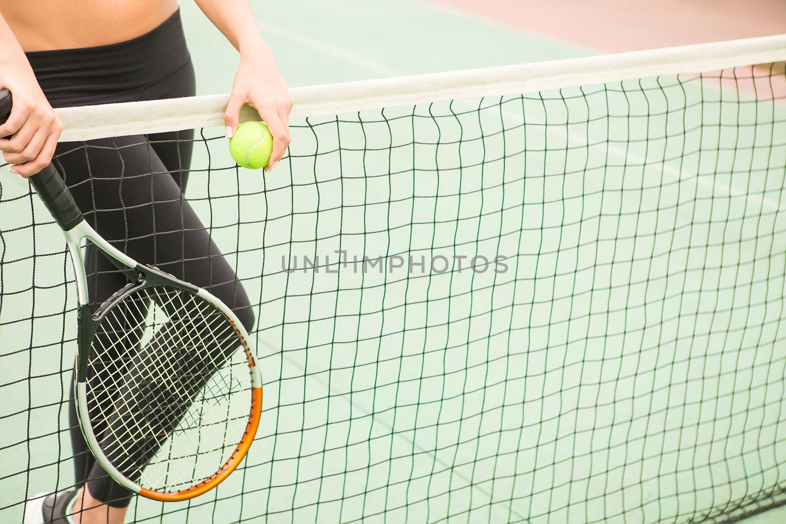 young woman with yellow ball and racket near net