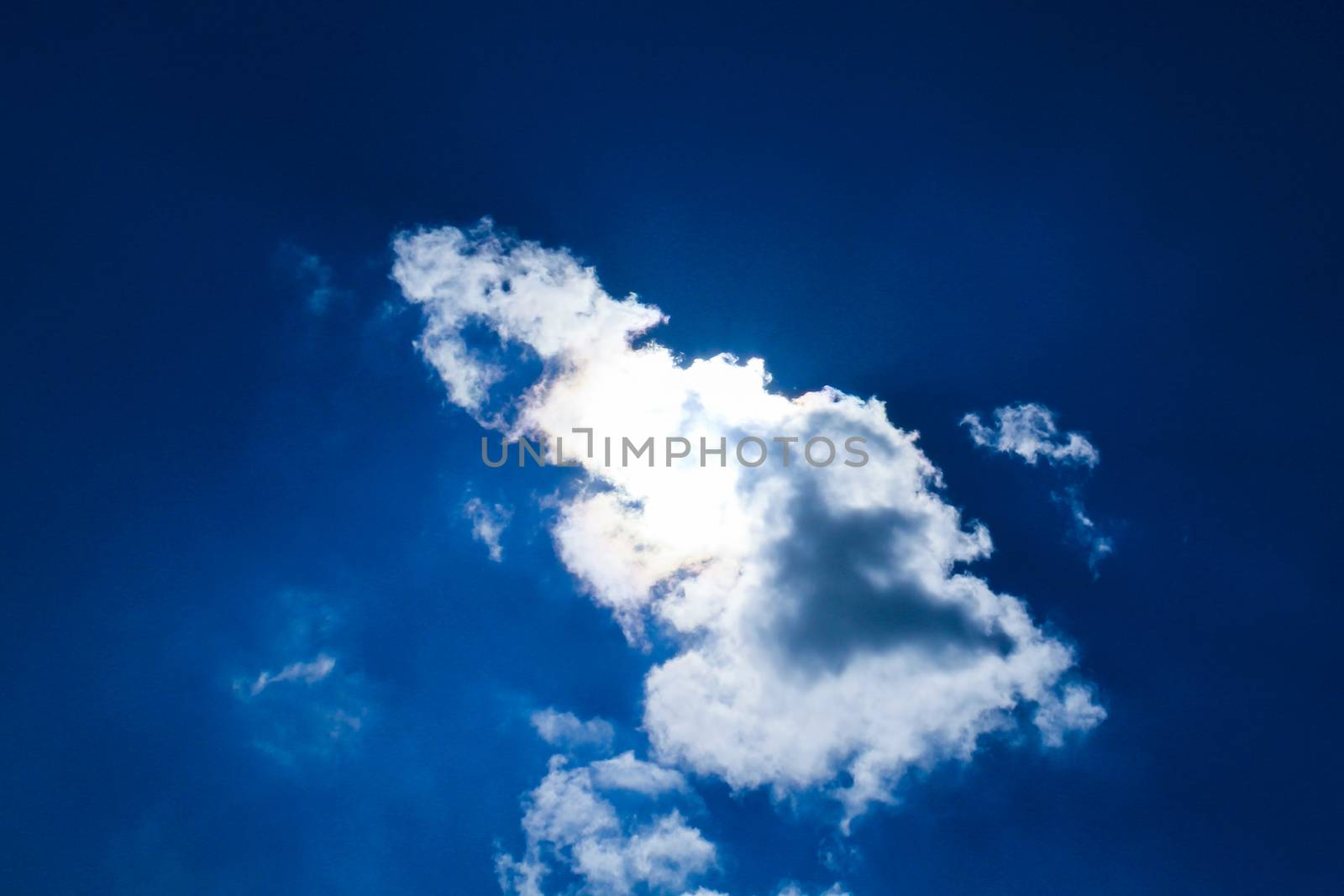 the sun behind a cloud, in a clear blue sky