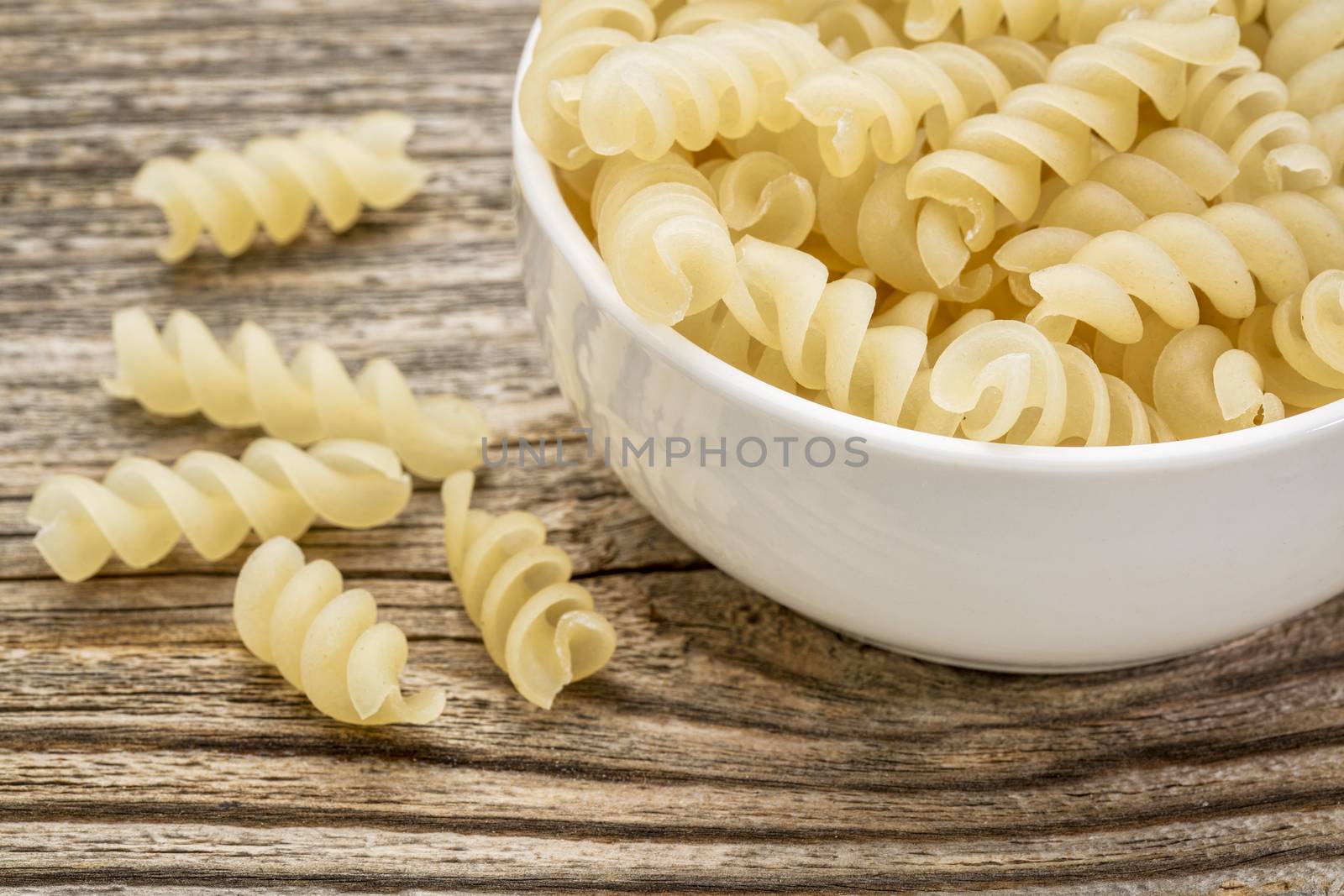 healthy, gluten free quinoa pasta (fusilli)  - small ceramic bowls against grained wood