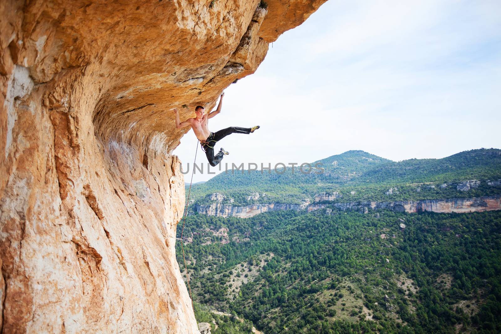 Male rock climber on challenging route on cliff by photobac