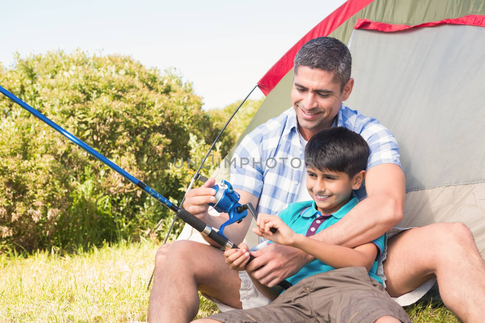 Father and son beside their tent on a sunny day