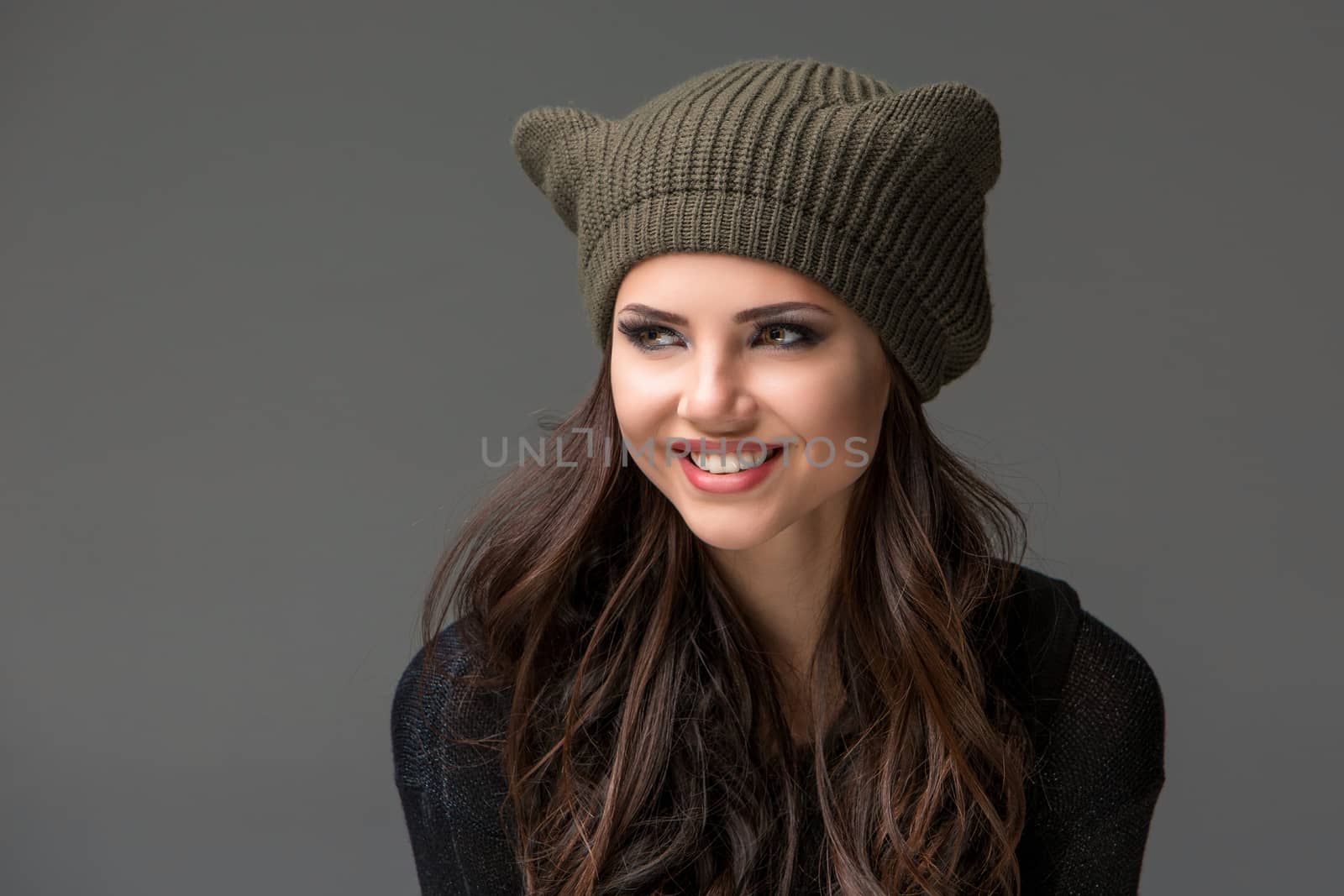 Beautiful sexy young woman in a  funny hat with ears smiling on gray background