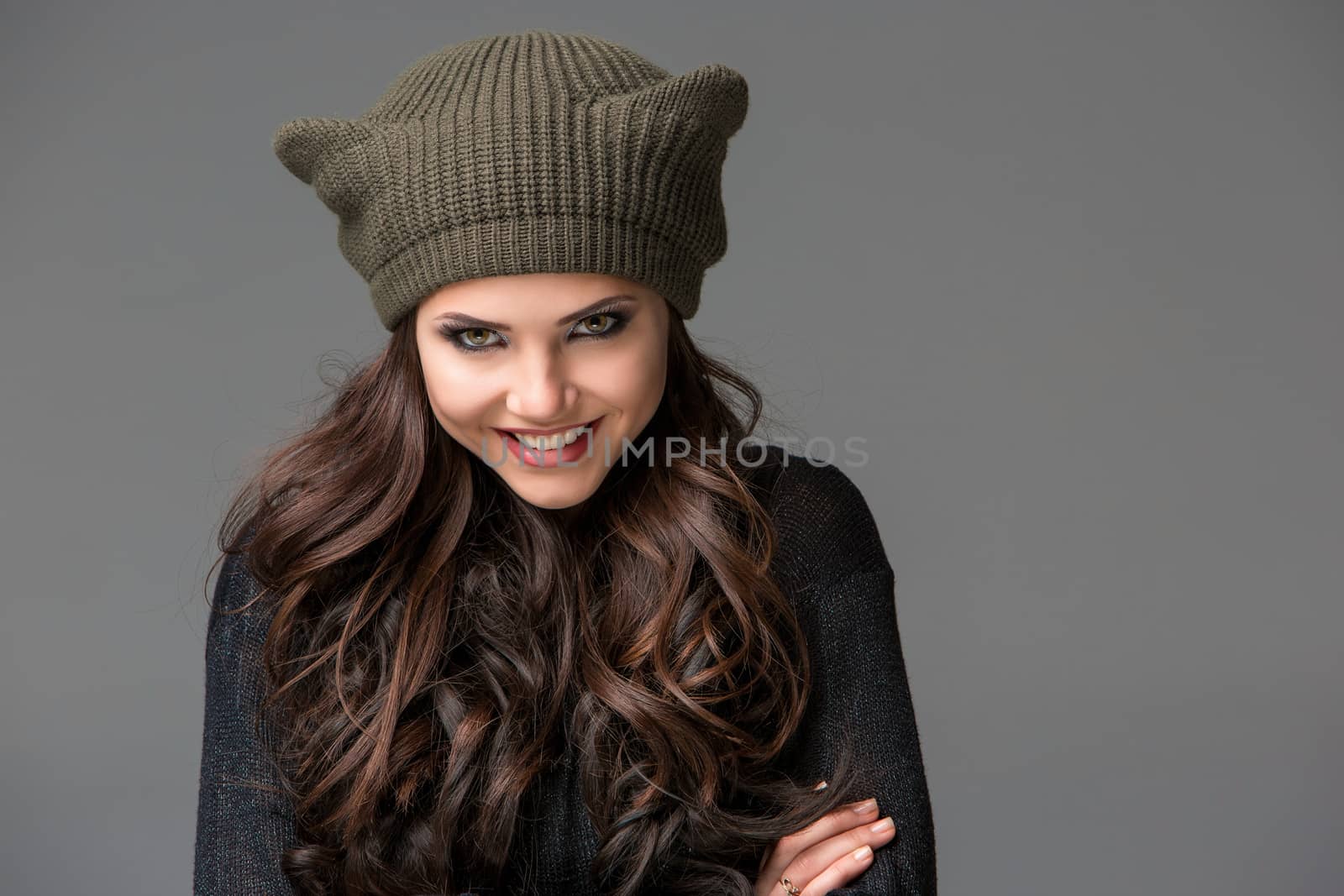 Beautiful sexy young woman in a  funny hat with ears smiling on gray background