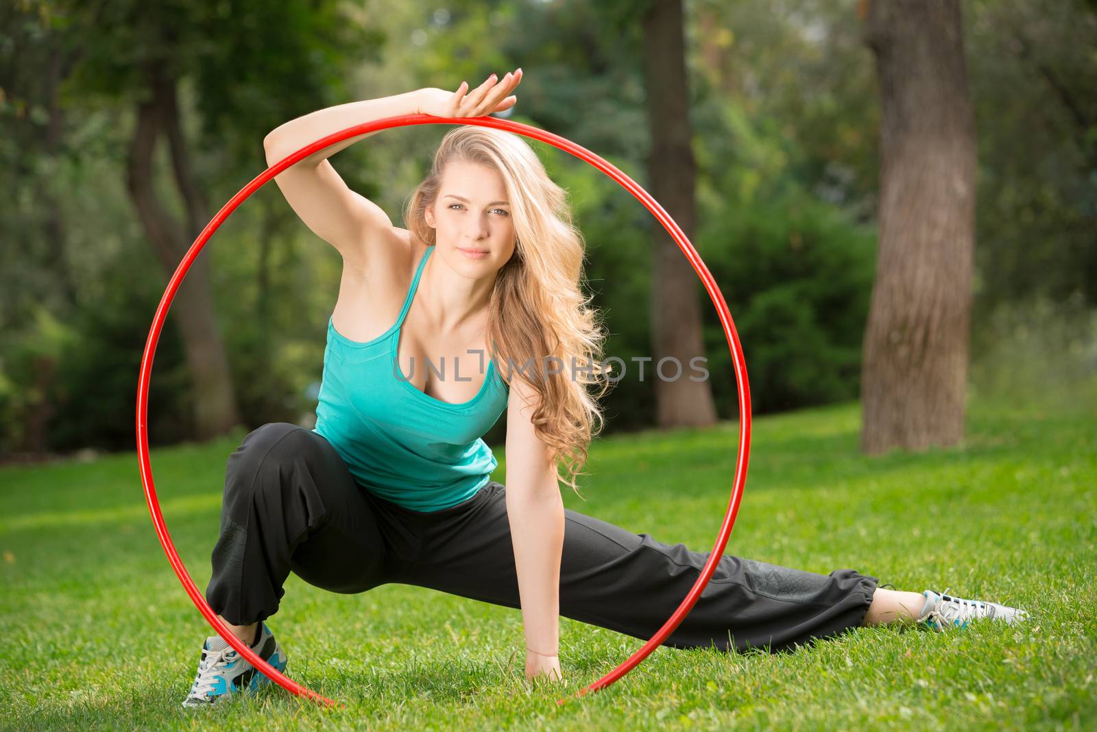 Young female athlete inside hula hoop in the park. Green grass backgruond