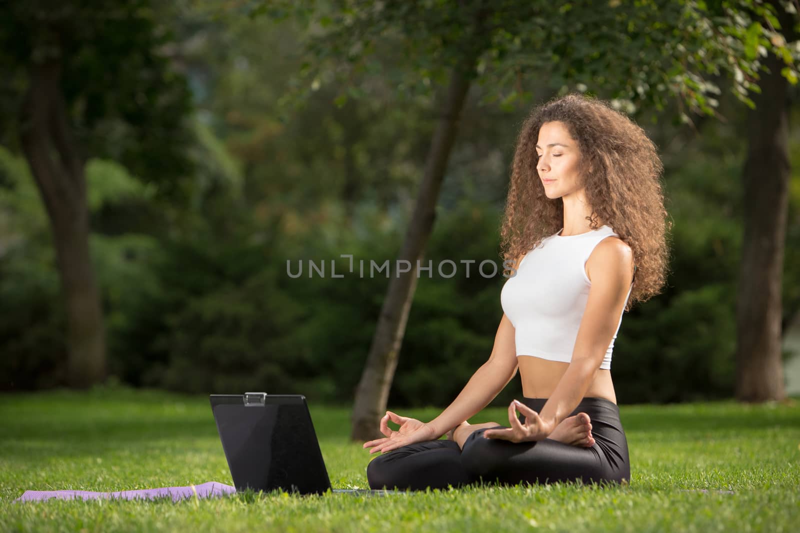Pretty woman doing yoga exercises in outdoor park,  green grass background 