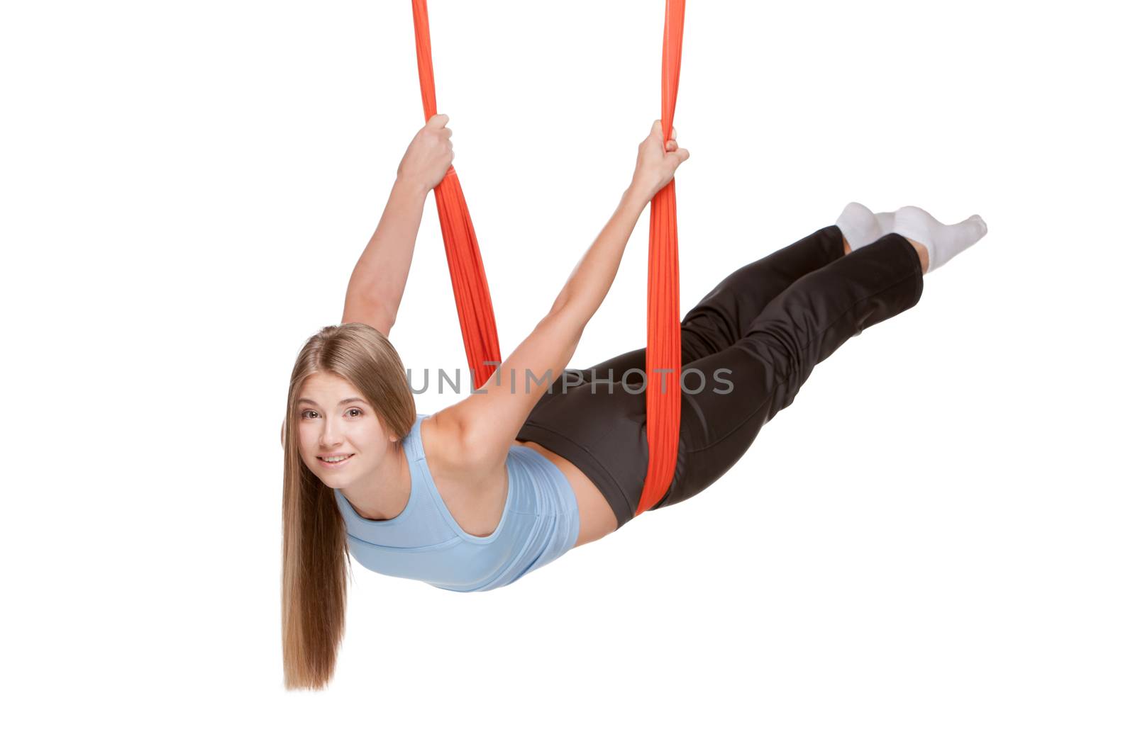 Young woman doing anti-gravity aerial yoga in red hammock on a seamless white background.
