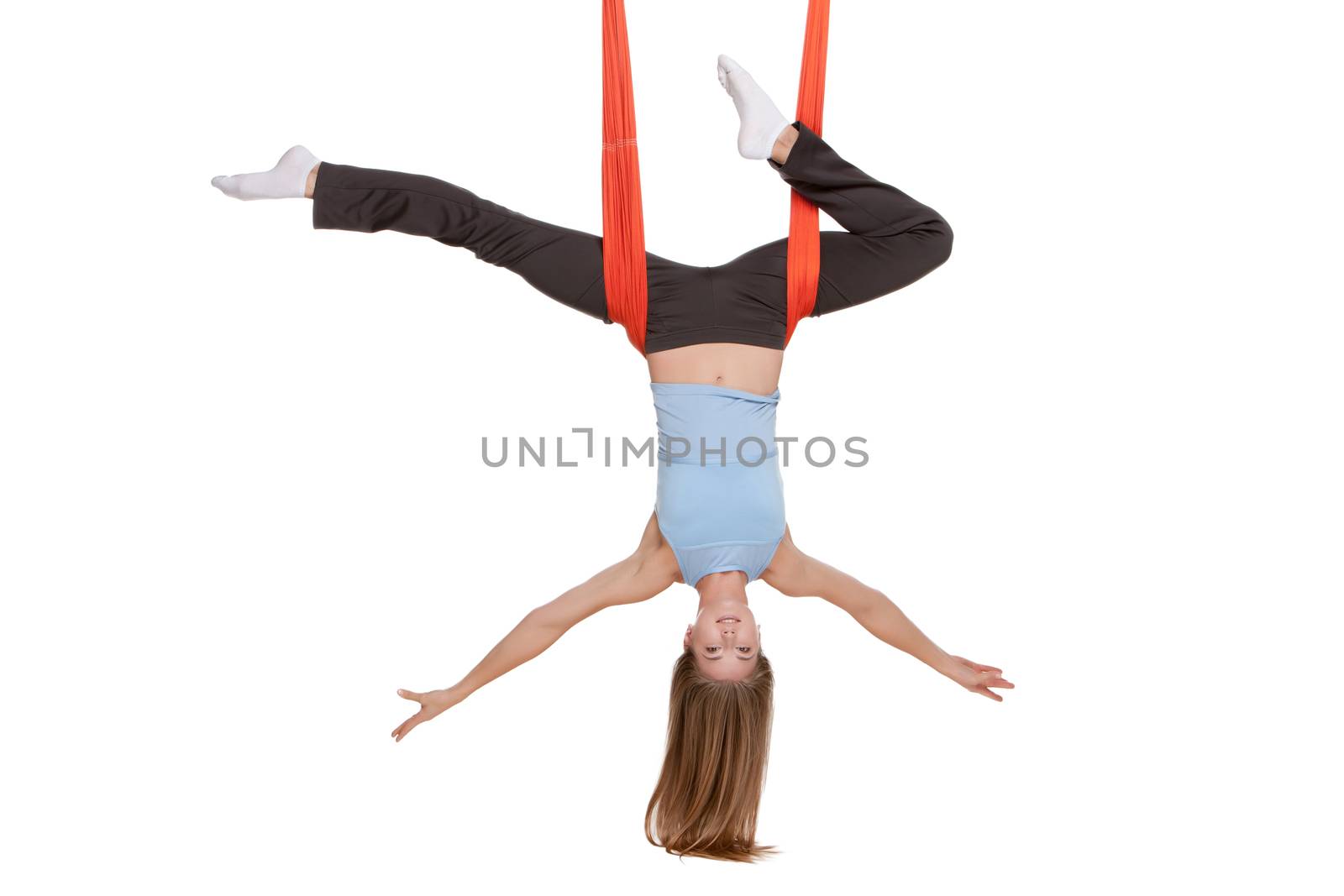 Young woman upside down doing anti-gravity aerial yoga in hammock on a seamless white background.