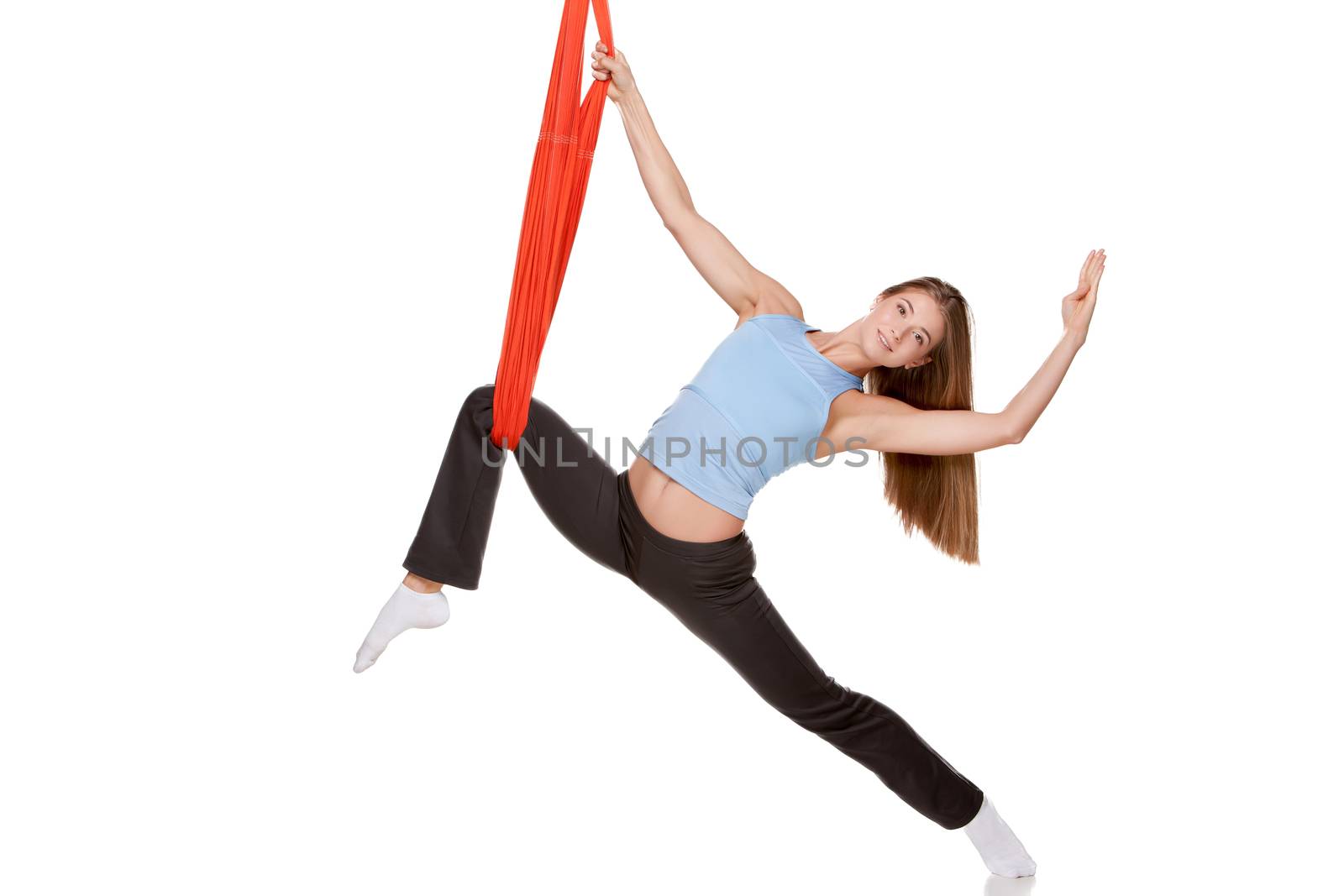 Young woman doing anti-gravity aerial yoga in red hammock on a seamless white background.