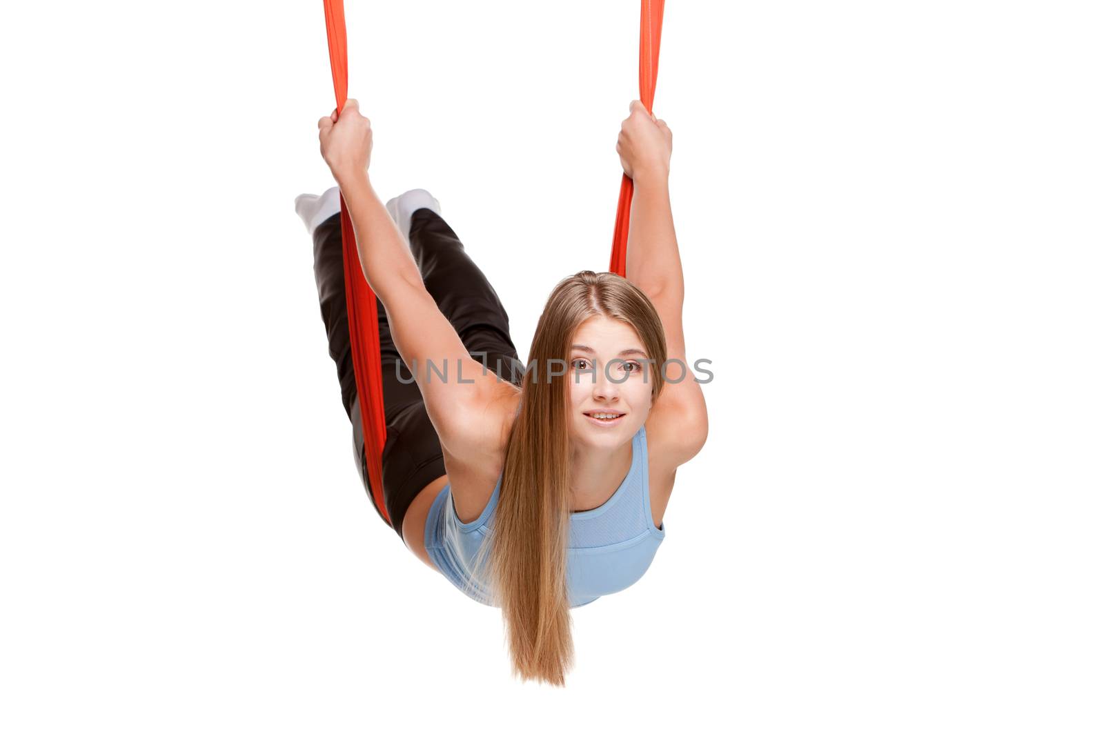 Young woman doing anti-gravity aerial yoga in red hammock on a seamless white background.