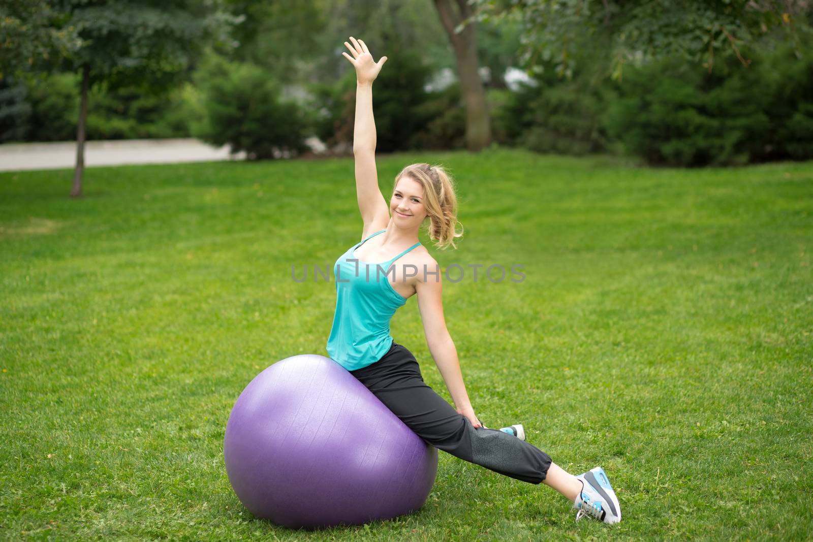 Young happy woman with fitness ball, outdoor. Green grass background 