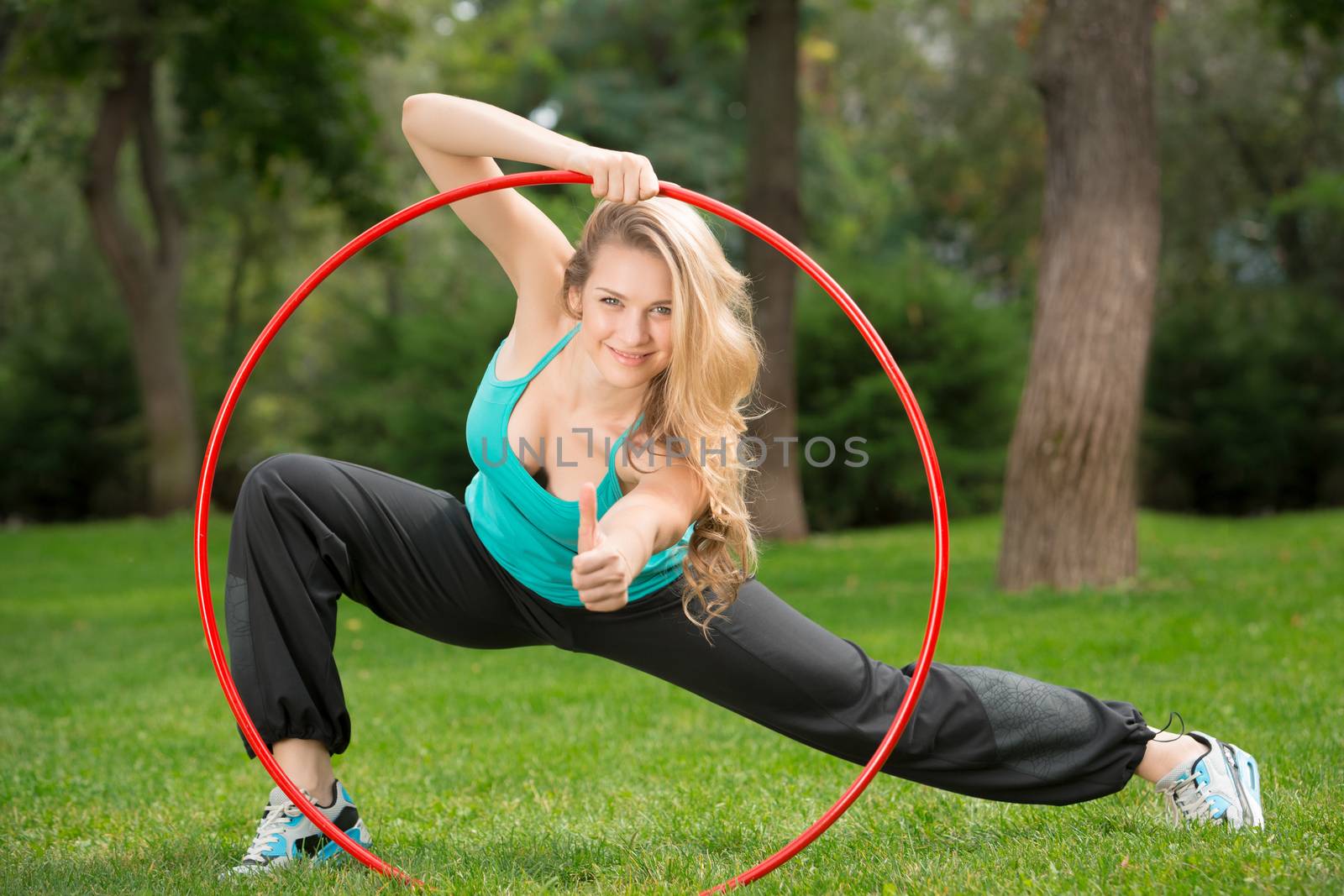 Young female athlete with hula hoop in the park by master1305