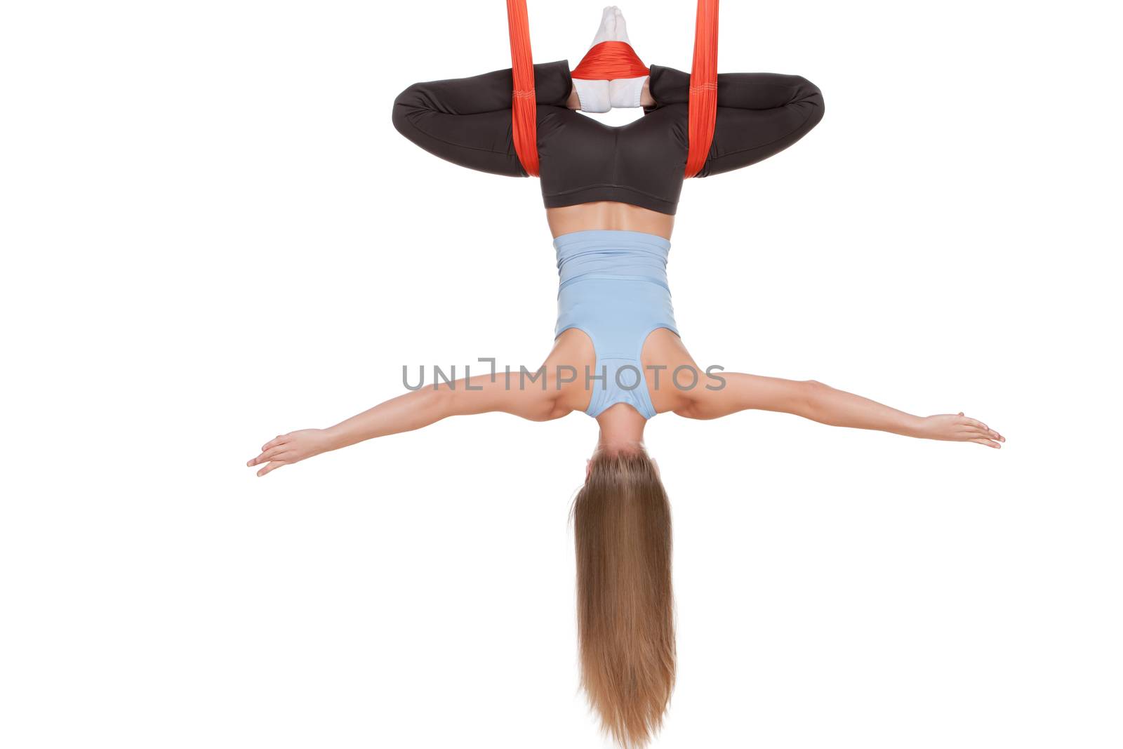 Young woman upside down doing anti-gravity aerial yoga in hammock on a seamless white background.