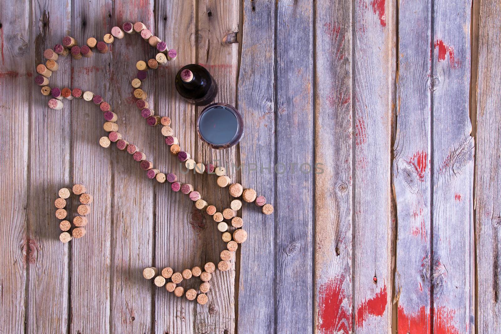 Wine lovers map of Italy formed from used red and white wine corks with a bottle and glass of red wine alongside on rustic wooden boards with copyspace, overhead view