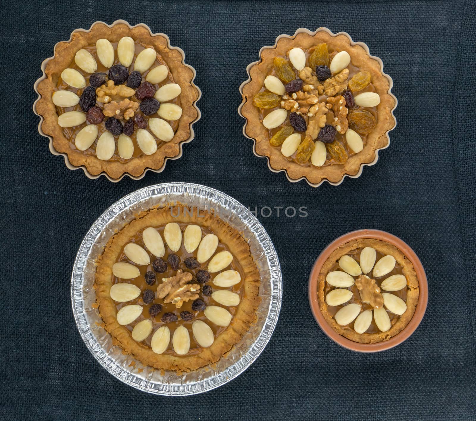 Four round traditional Polish Easter cakes with almonds, raisins and walnuts on the dark background.