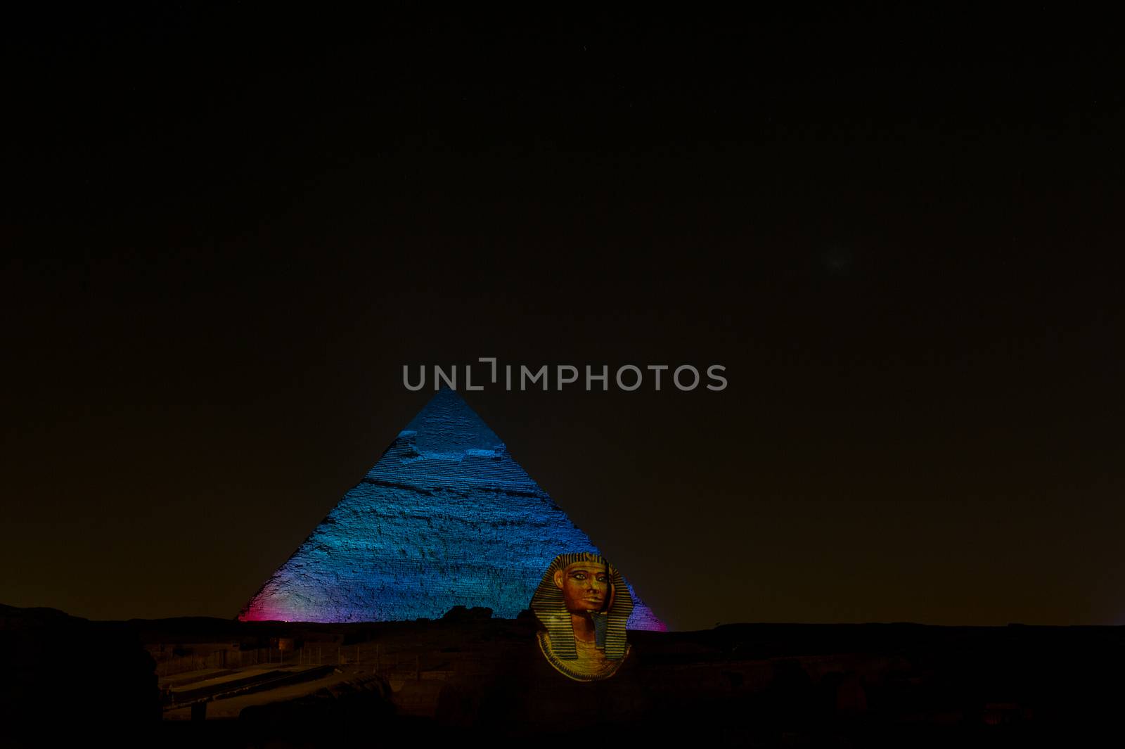 A row of camels transport tourists in front of all of the Giza Pyramids in Cairo, Egypt