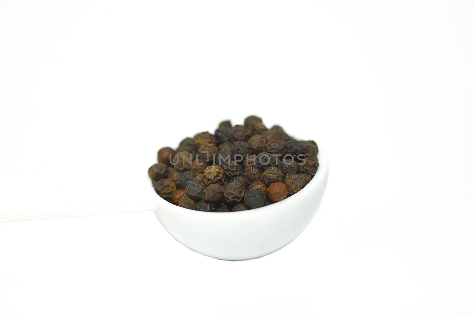 A spoon of black pepper isolated on white background