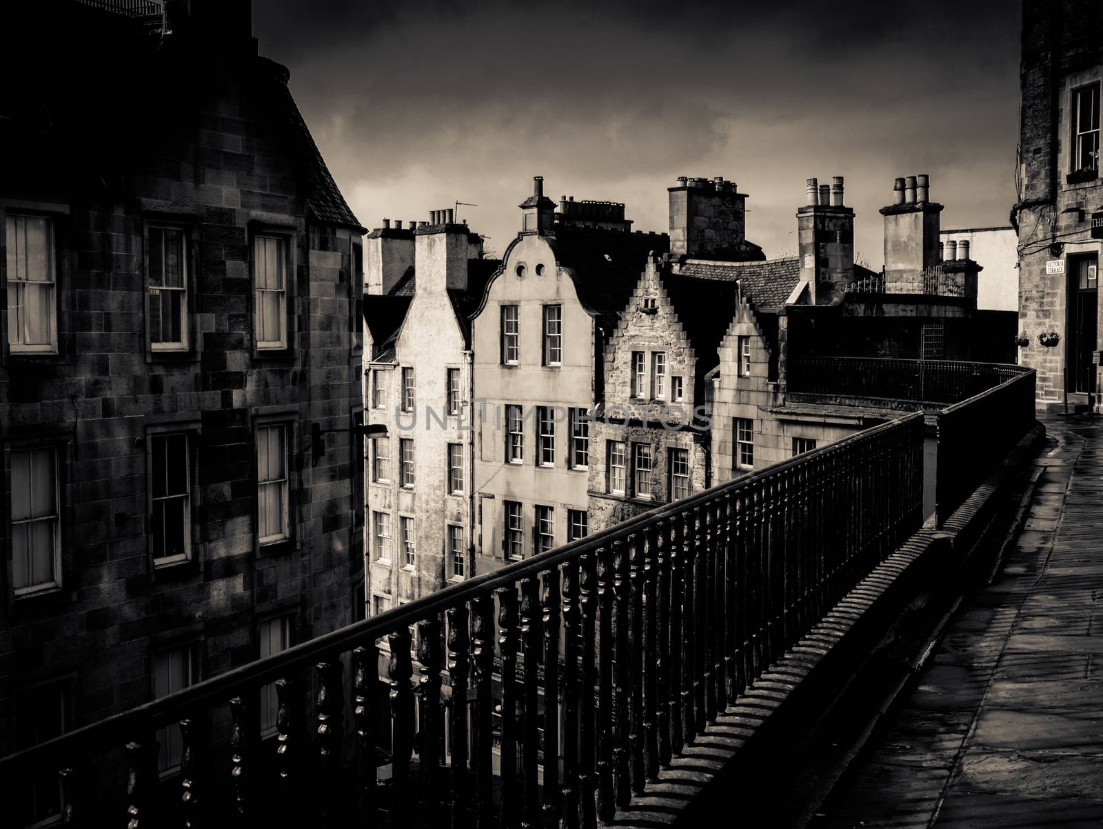 Black And White Image Of An Ancient Edinburgh Street Under A Stormy Sky