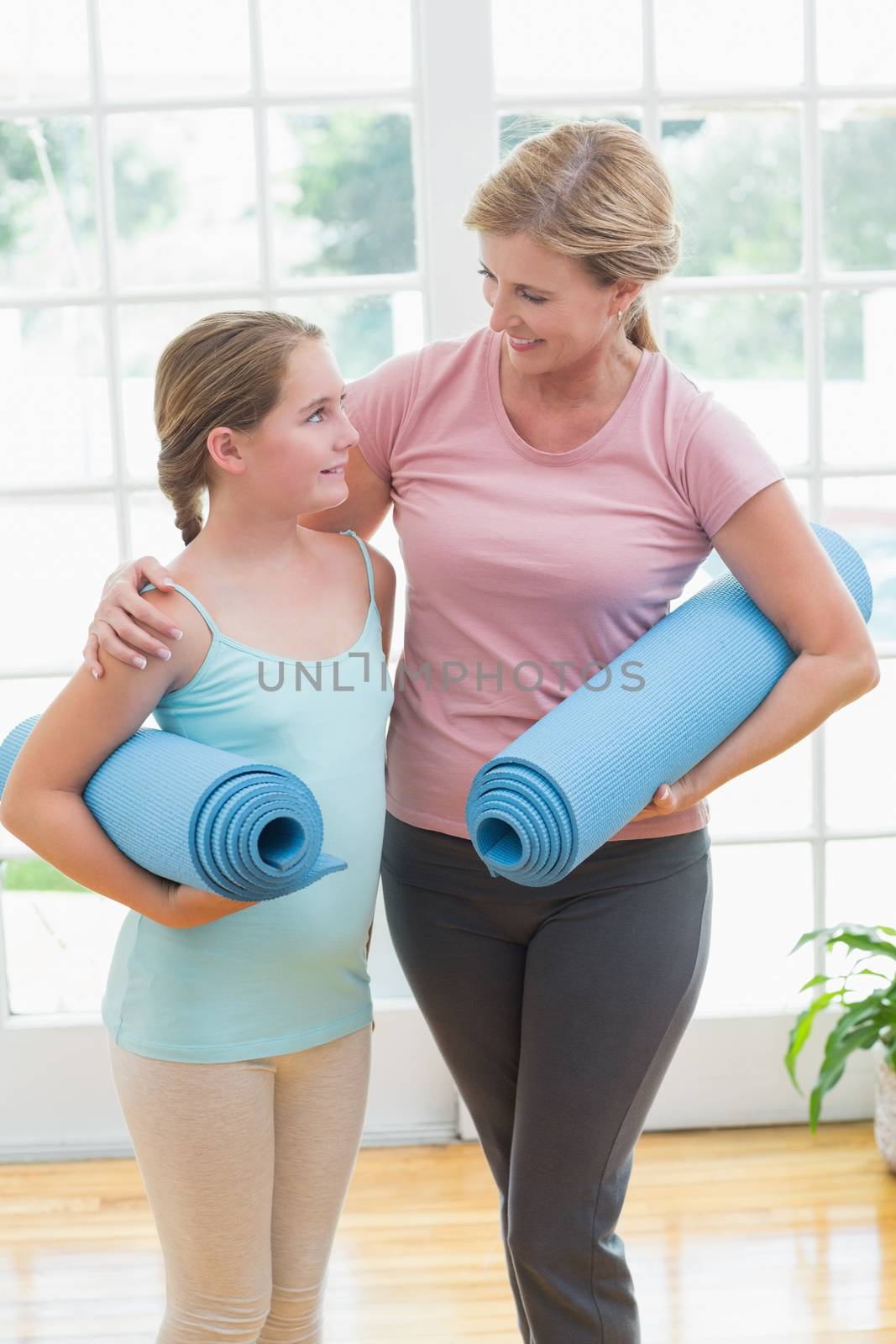 Mother and daughter holding yoga mats  by Wavebreakmedia