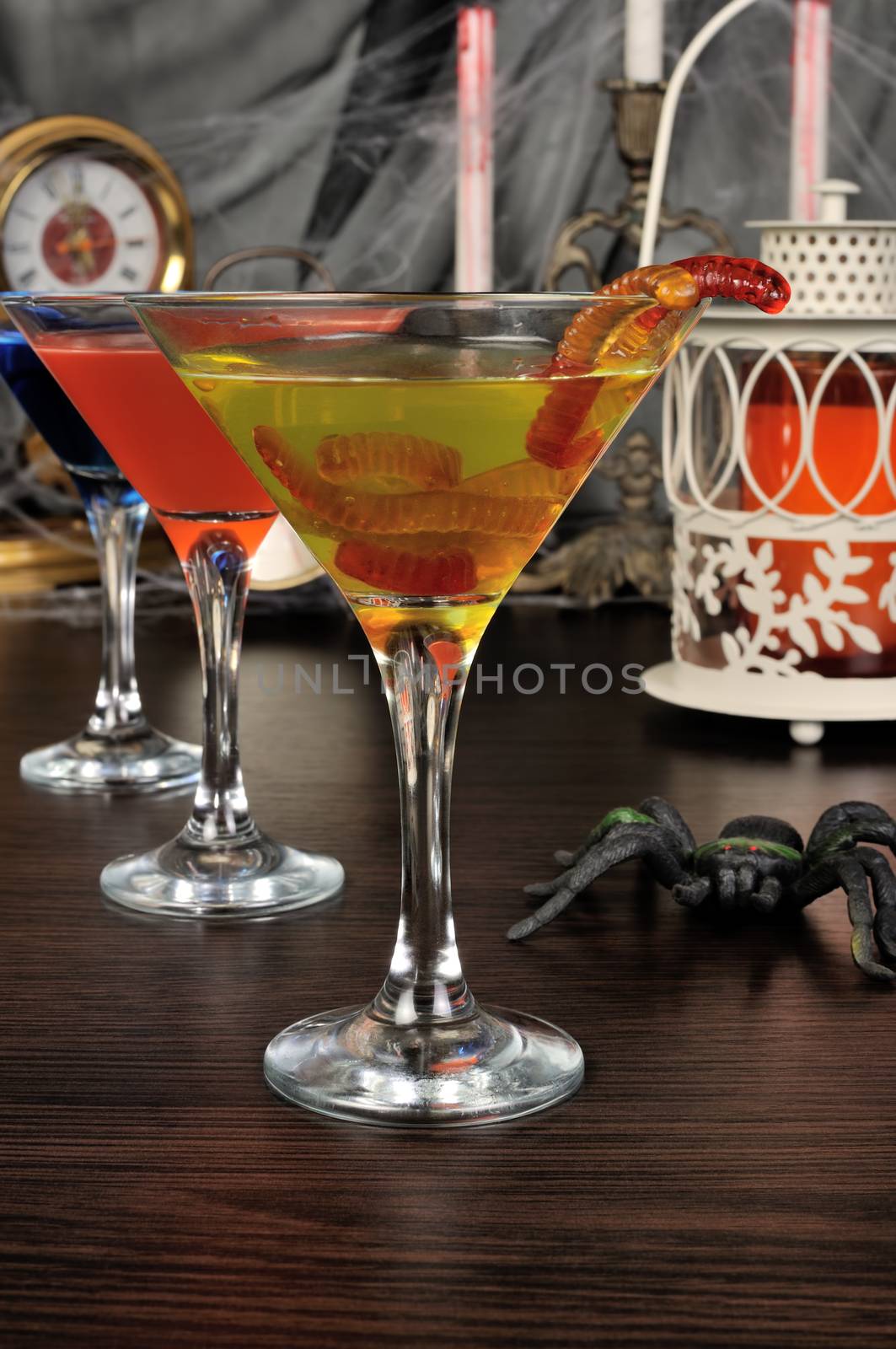 Cocktail glass filled drink and  jelly worms  on the table for Halloween