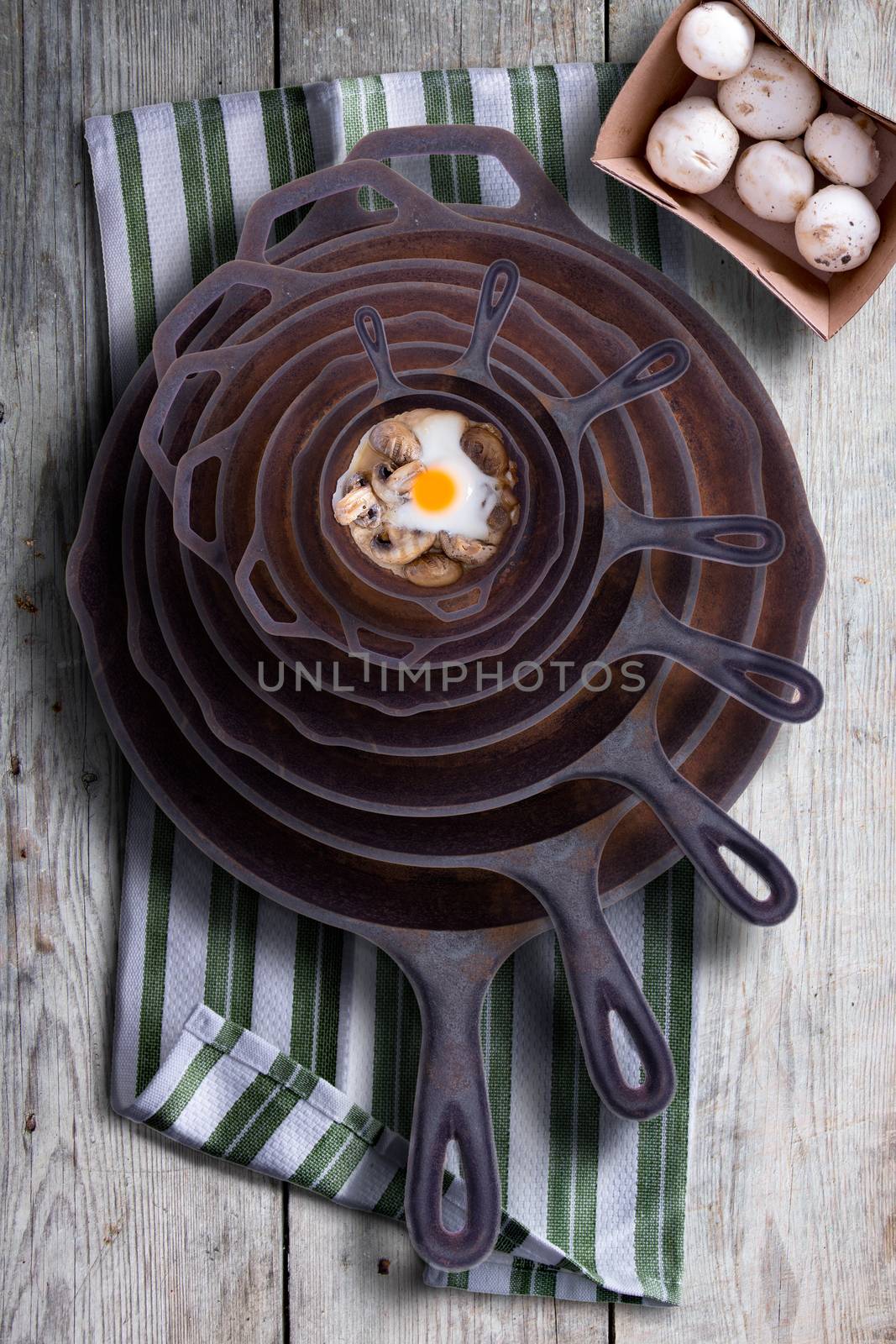 Egg and mushrooms in a stack of frying pans by coskun