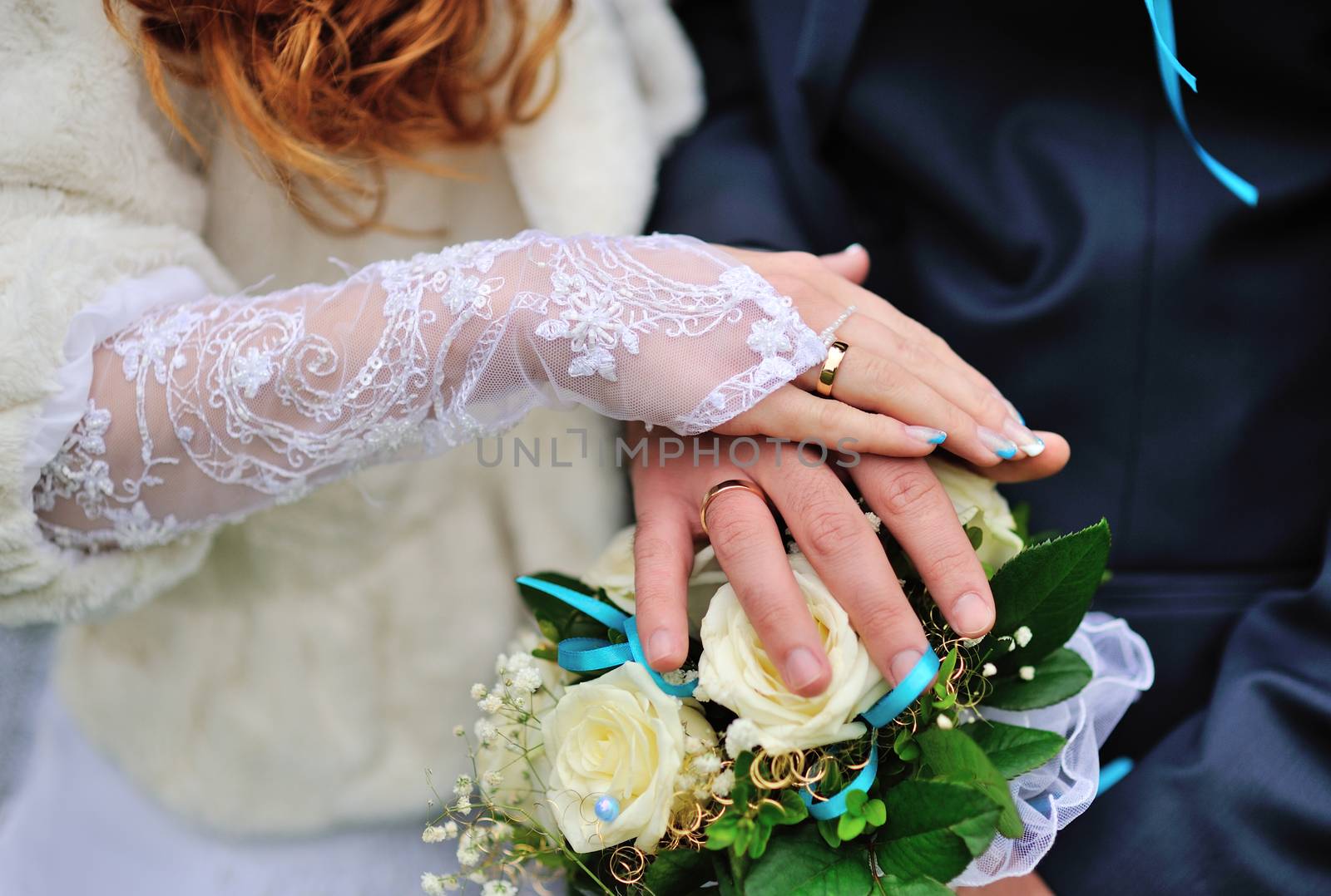 Hands of the groom and the bride on wedding bouquet