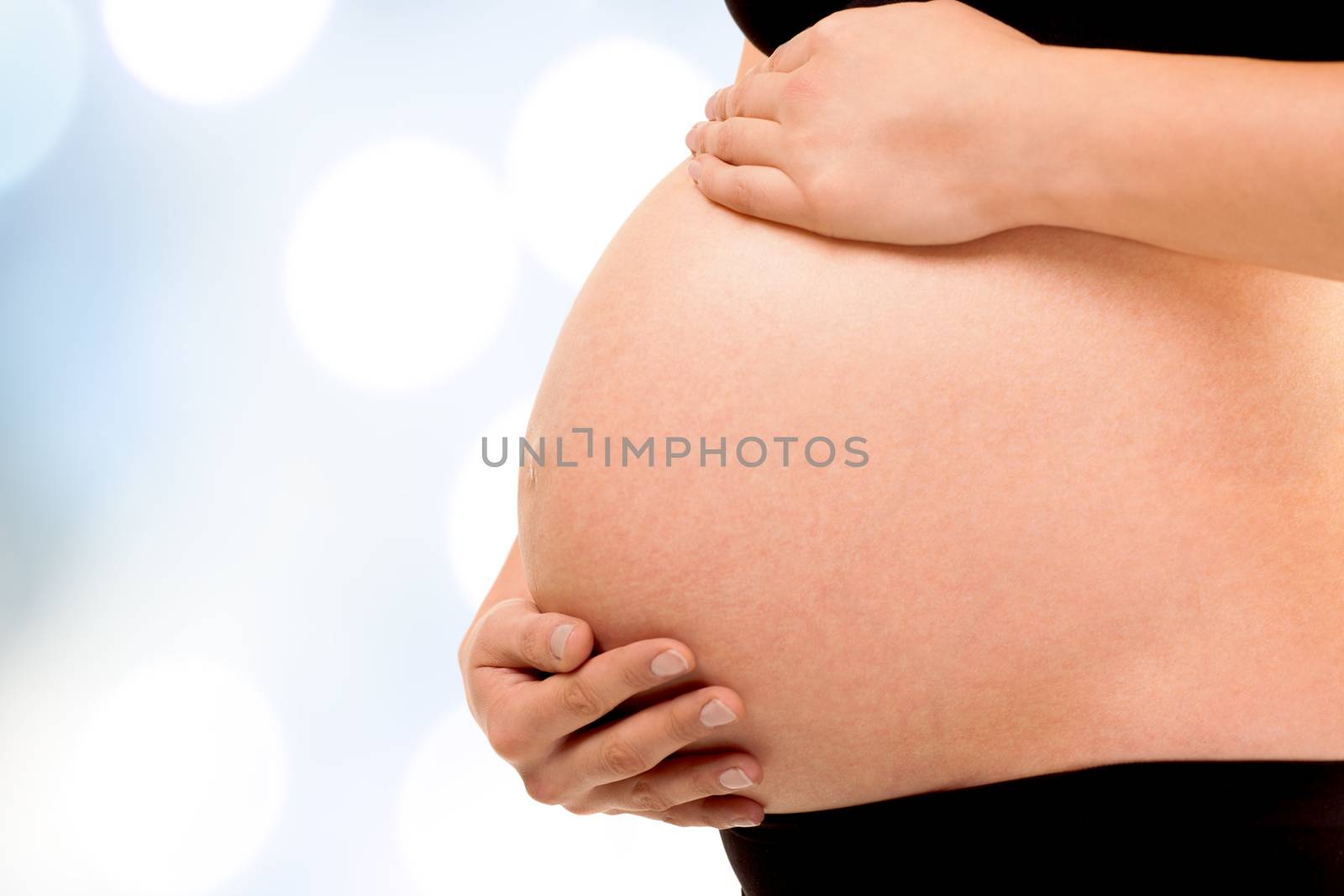 Pregnant woman holding gently her belly with two hands. Isolated background with work path.