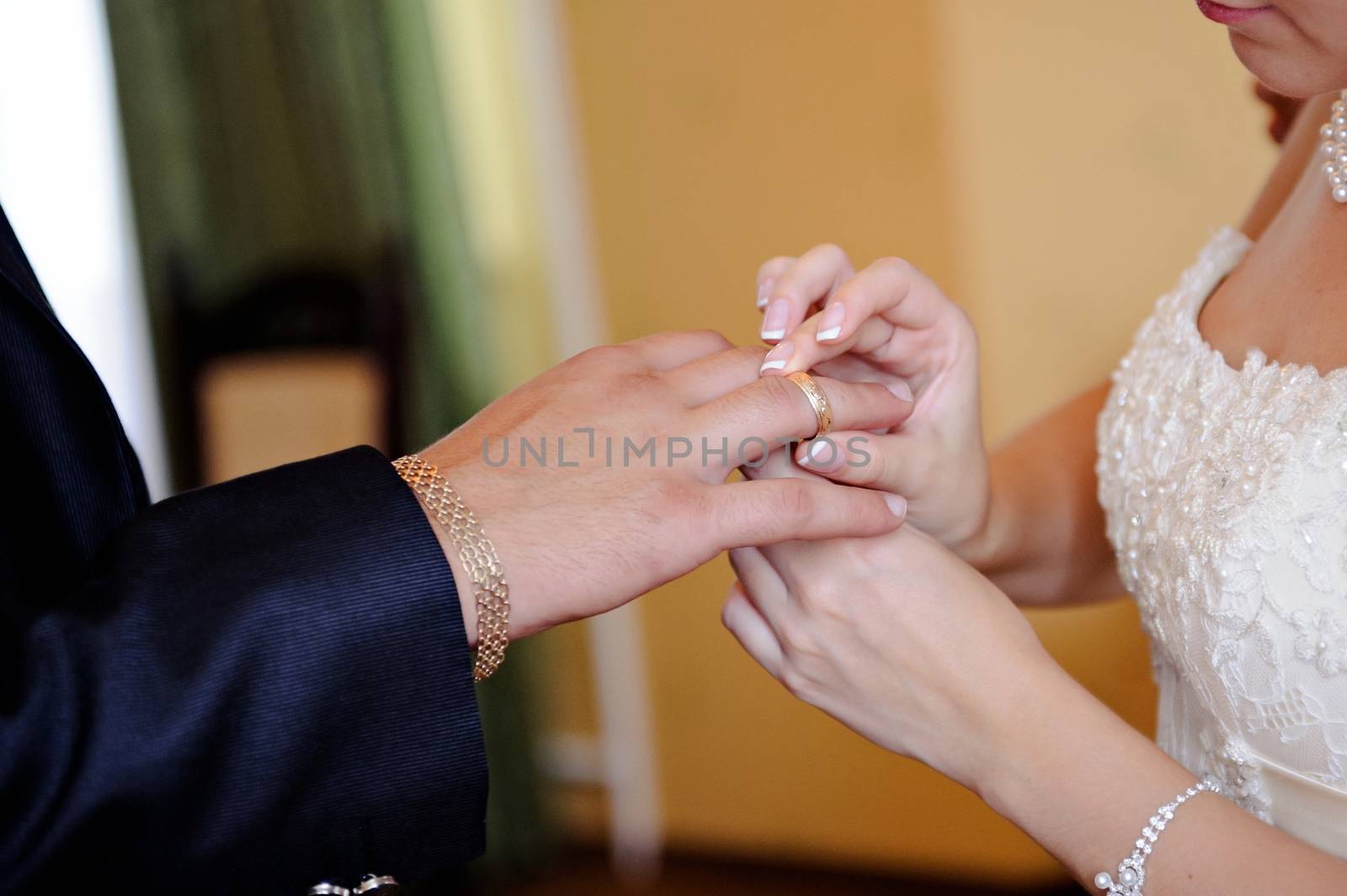Bride putting a wedding ring on groom's finger by timonko
