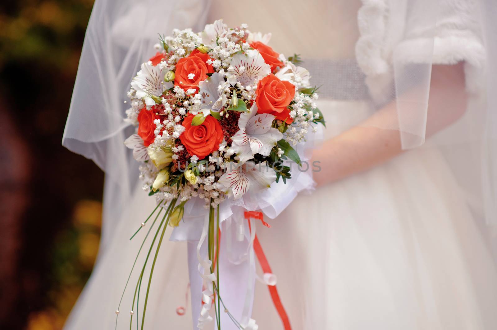 bride holding a wedding bouquet with white and red flowers