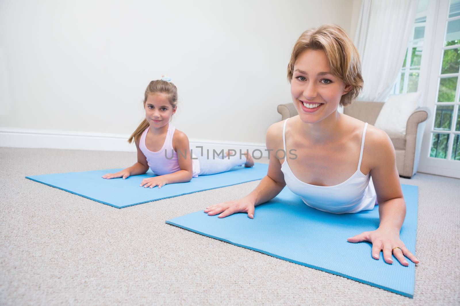 Mother and daughter doing yoga at home in the living room