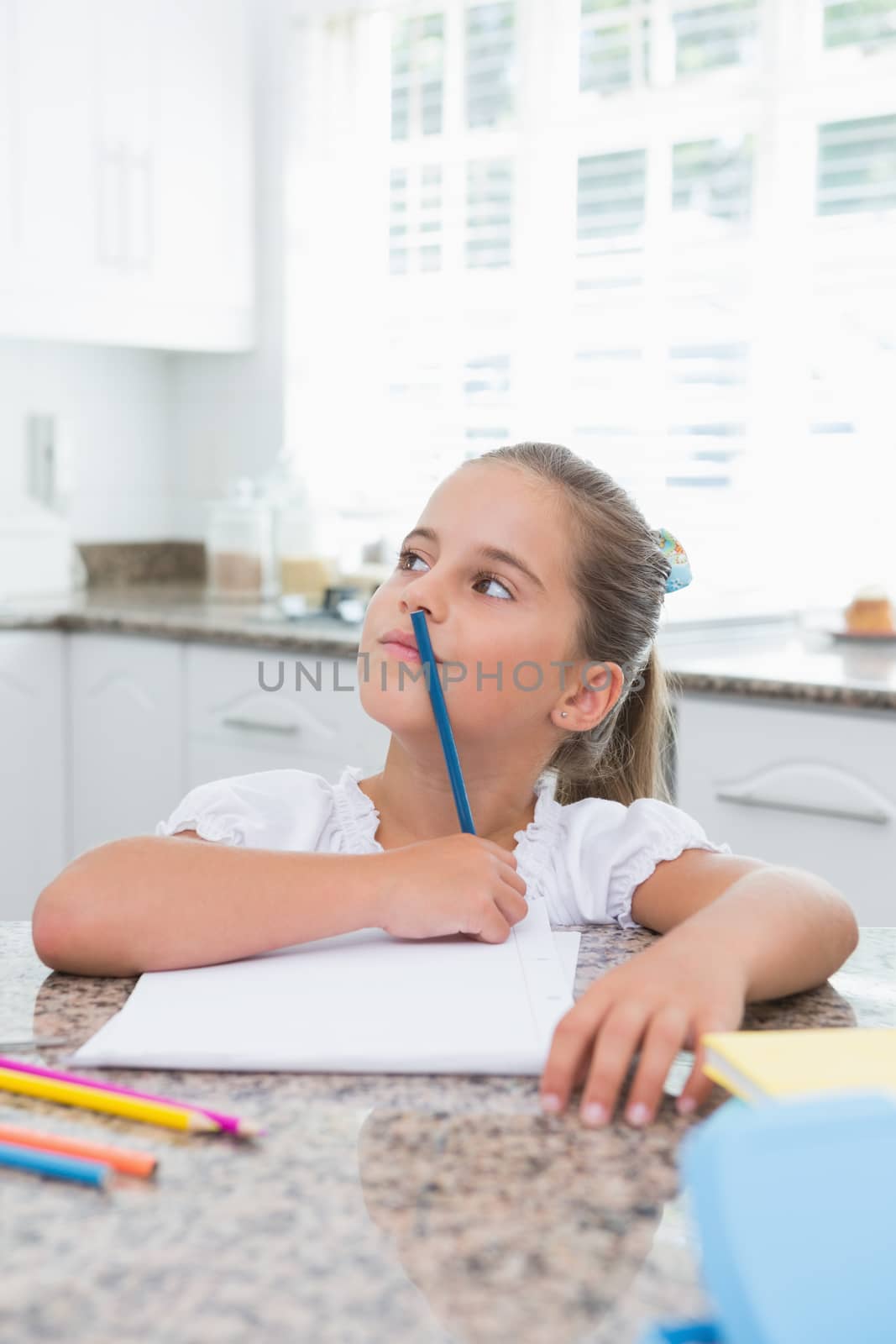 Little girl doing her homework at home in kitchen