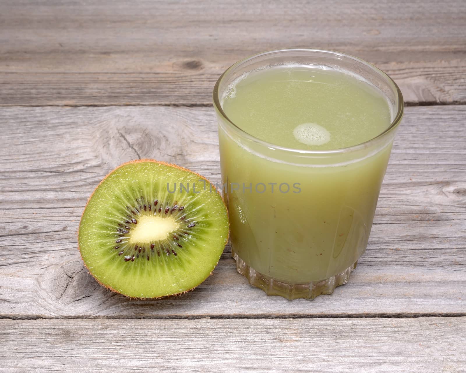 Glass of kiwi juice with fresh fruits isolated on wooden table by comet