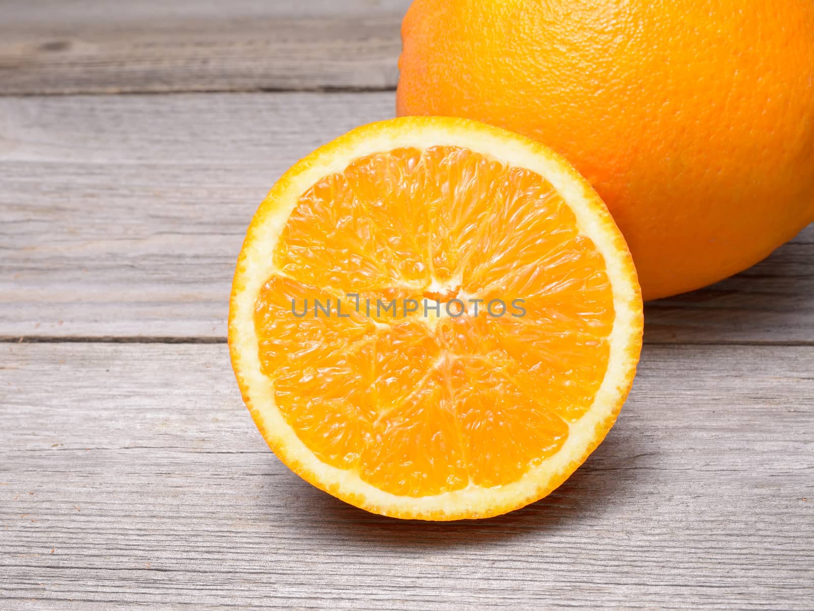 Glass of orange juice with sliced orange half on wooden table by comet
