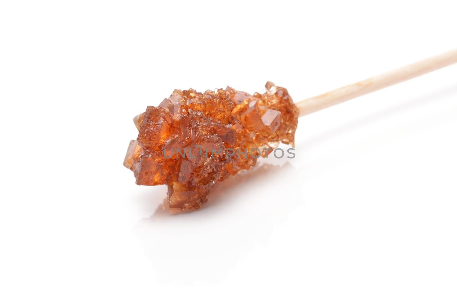 Brown sugar crystal on wooden stick isolated over white background by comet
