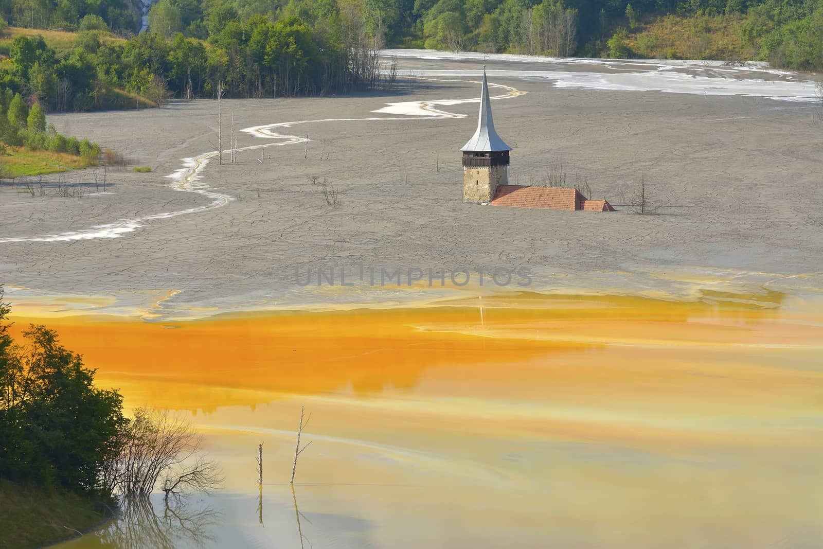 Red lake polluted with dead trees and a flooded church in Romania, Geamana