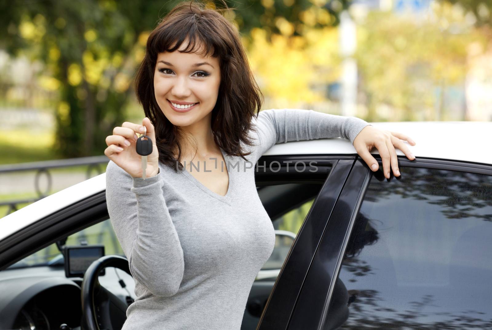 Pretty girl in a car showing the key.