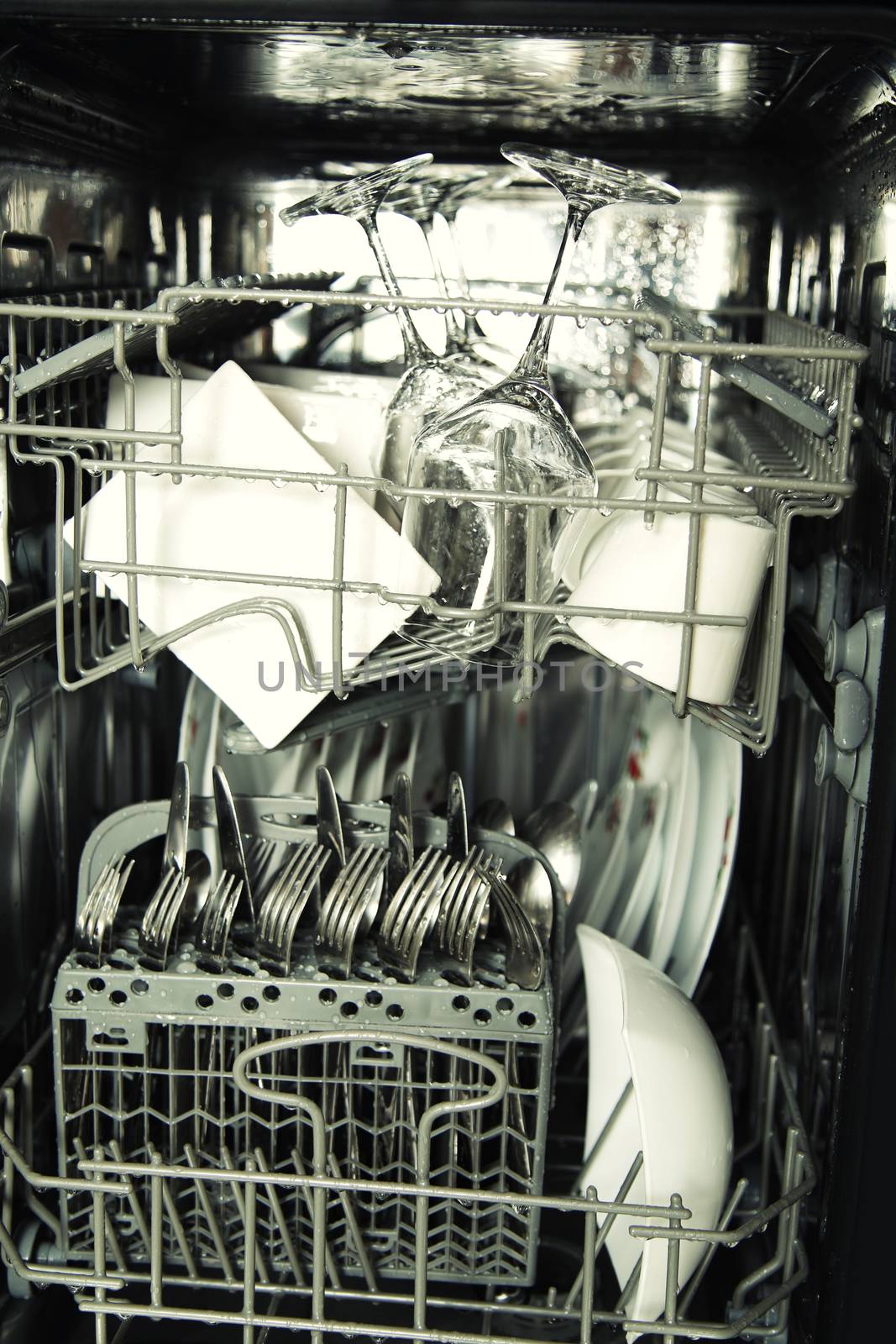 details of open dishwasher, utensils with drops in during washin by vladacanon