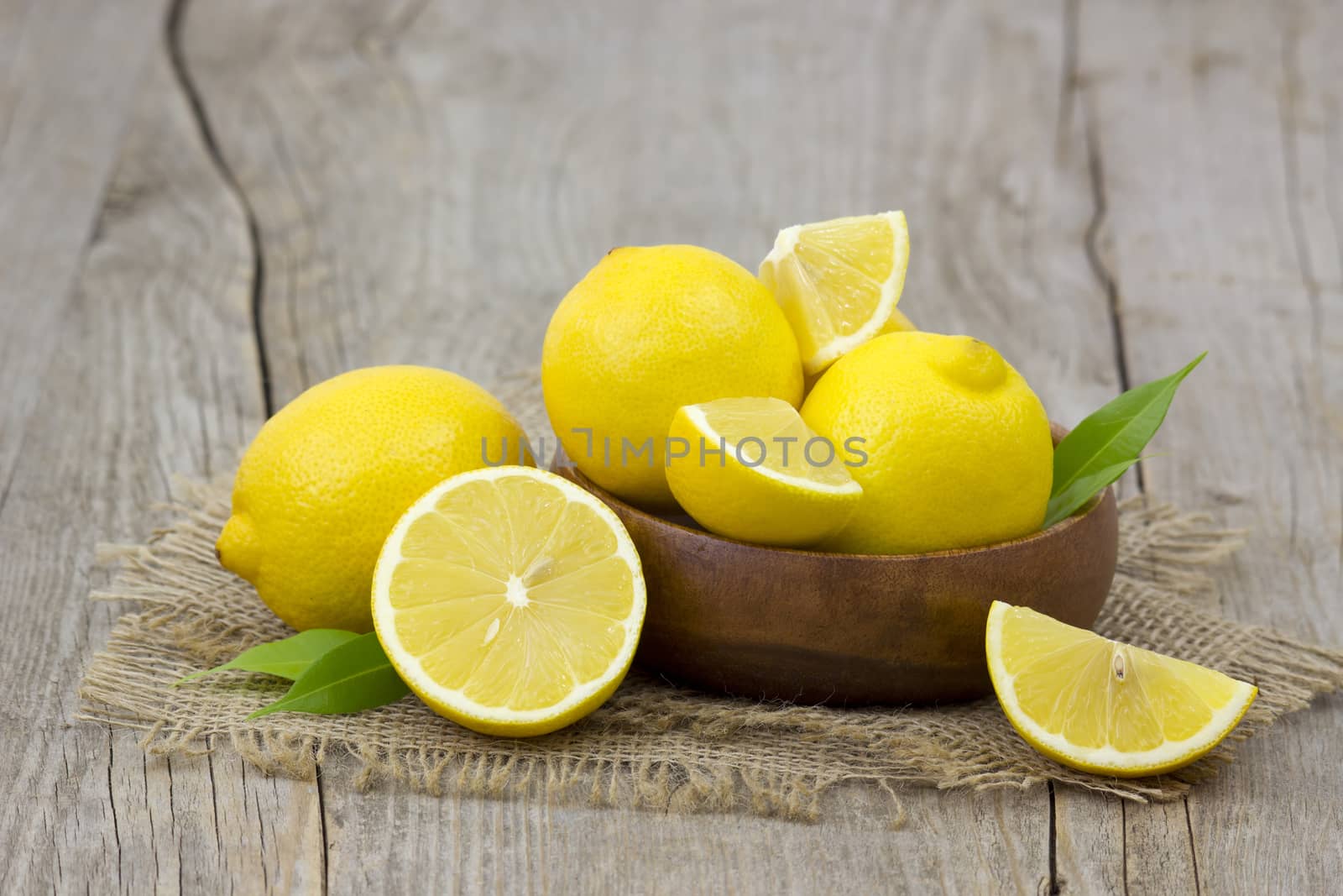 fresh lemons in a bowl on wooden background