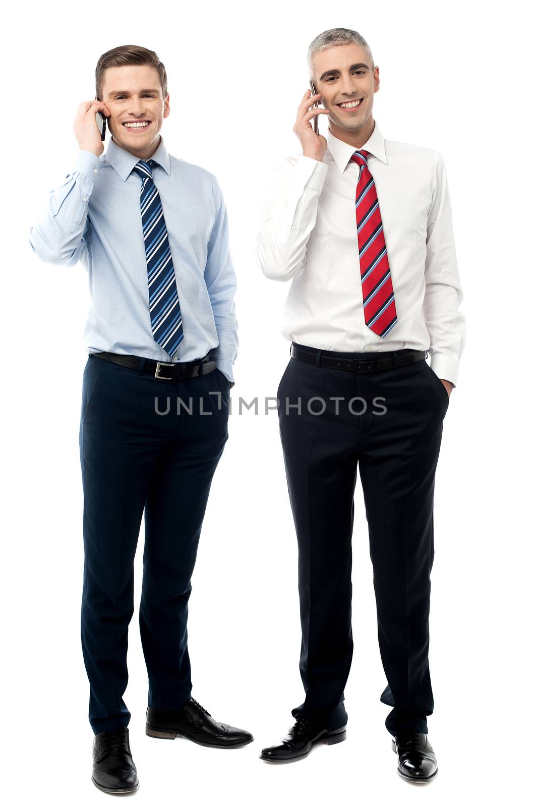 Two male executives talking on cellphone by stockyimages