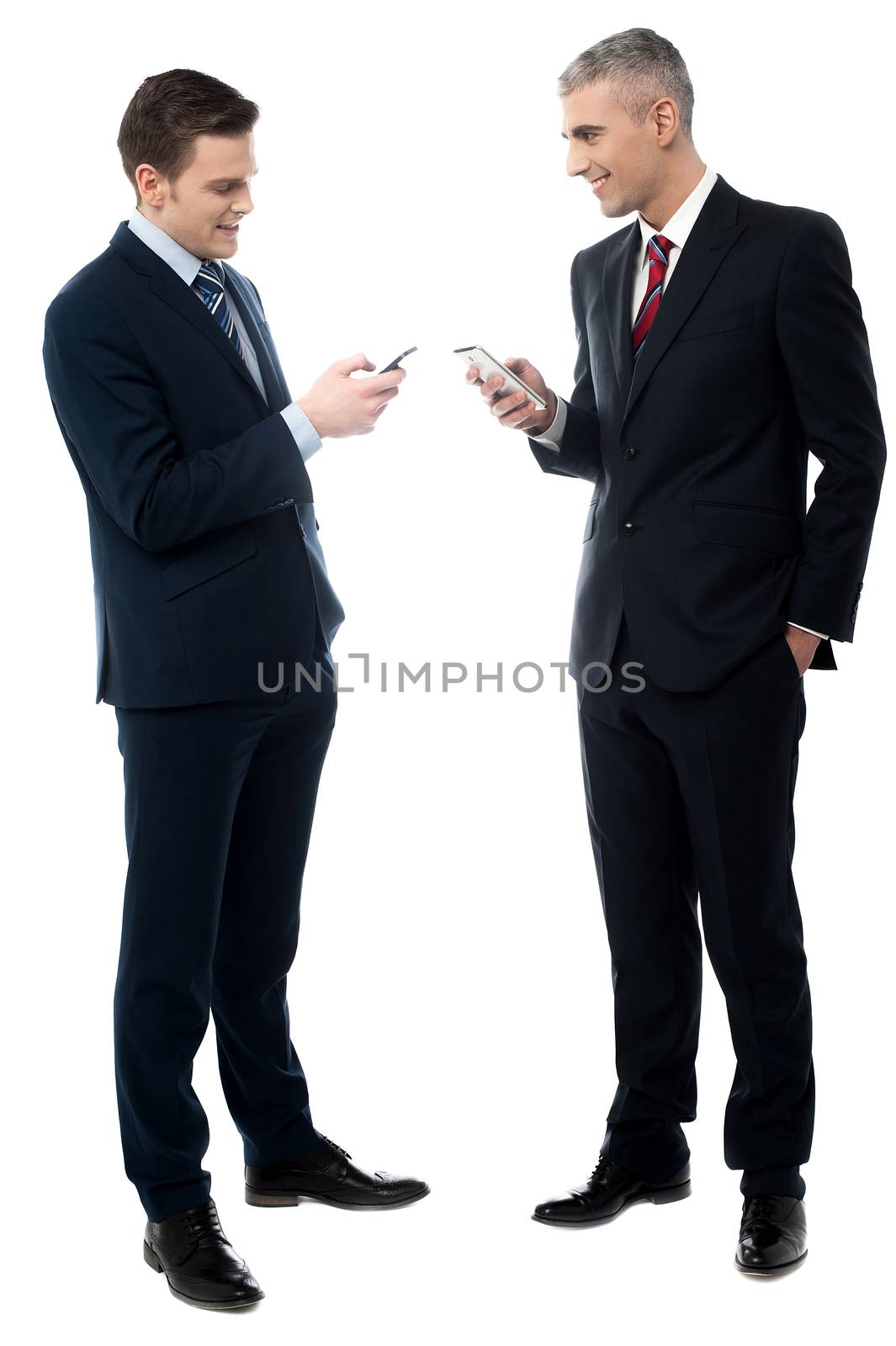 Full length of business people discussing with cell phone