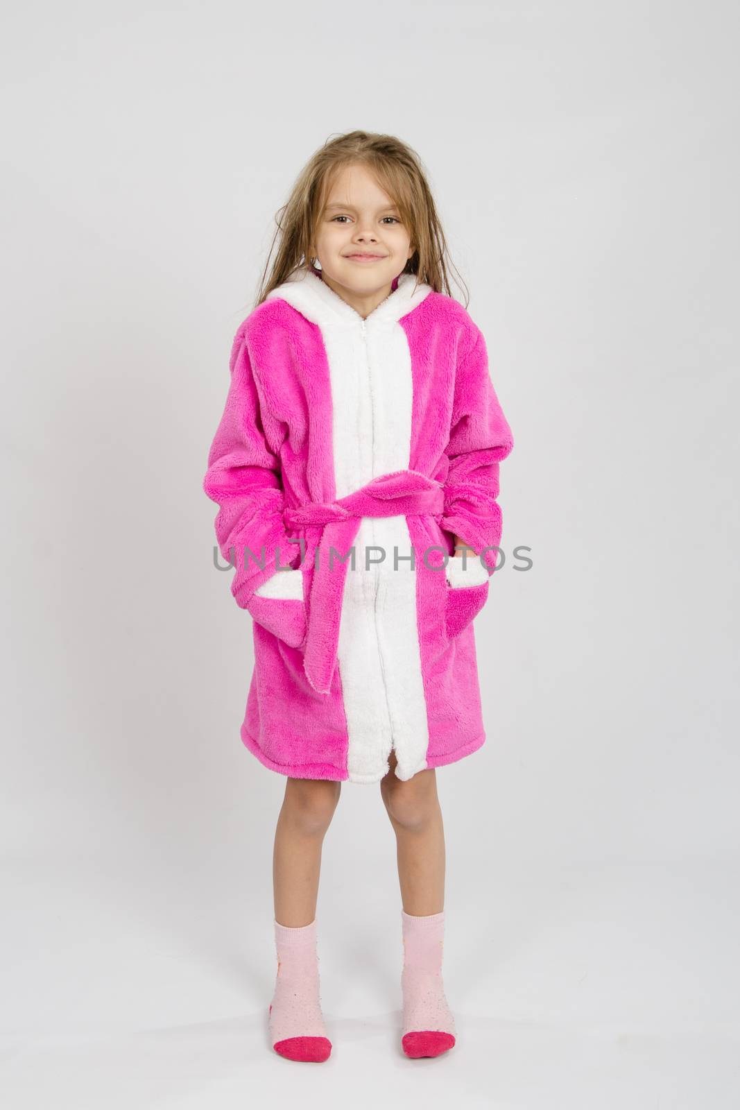 Six year old girl with wet hair in a bathrobe on a light background