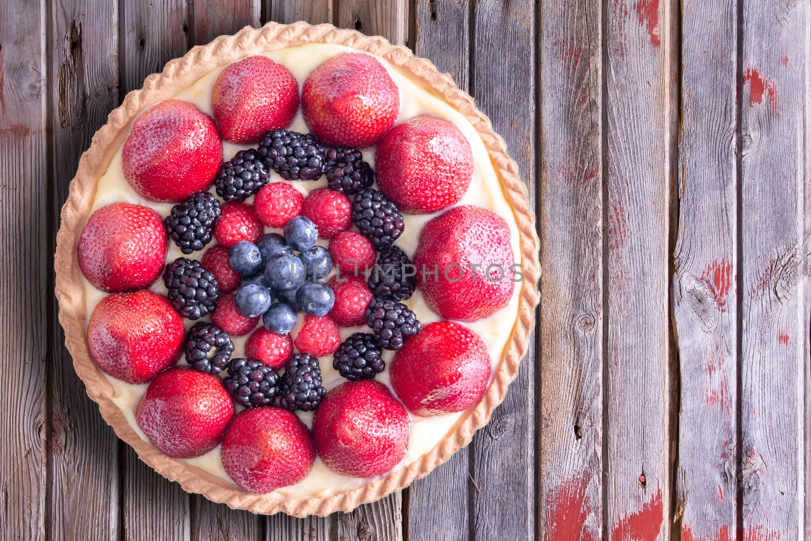 Close up Tasty Homemade Tart with Fresh Berry Fruits on Top of a Rustic Table, Captured in High Angle View.