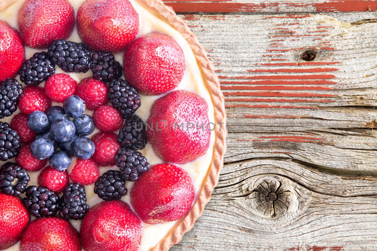 Tart with Fresh Berries on Rustic Wooden Table by coskun