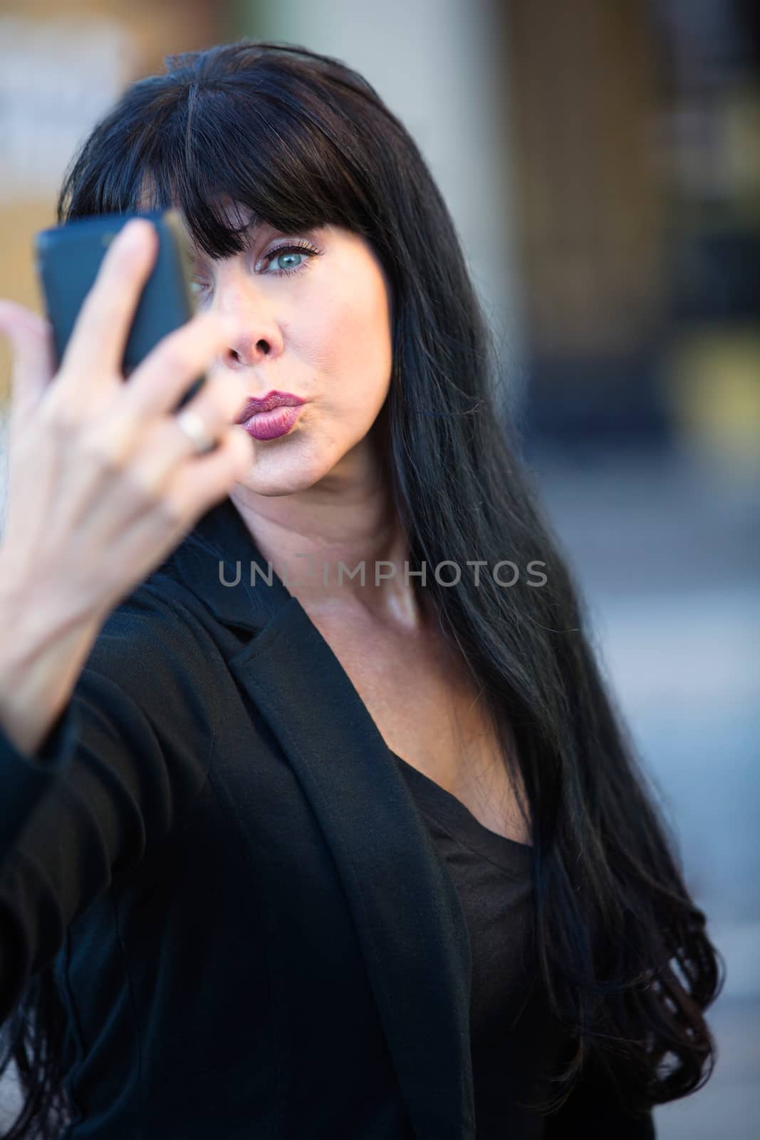 Pretty woman in downtown setting puckers her lips for a selfie