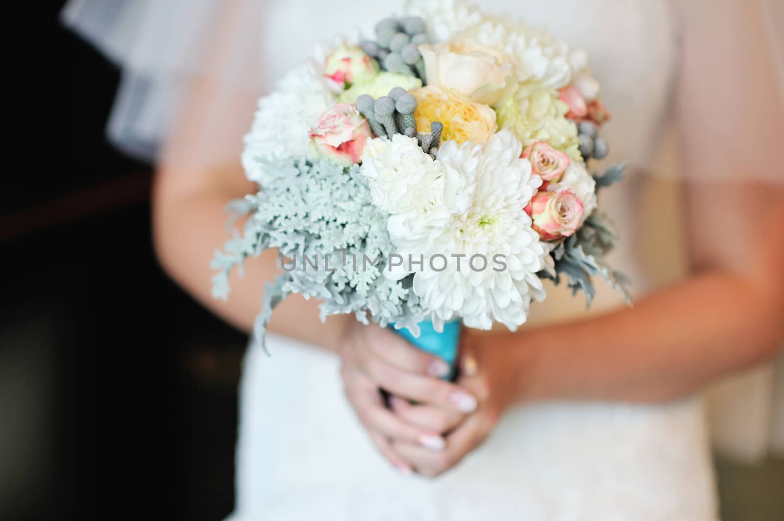 Wedding bouquet of white roses in bride's hands 