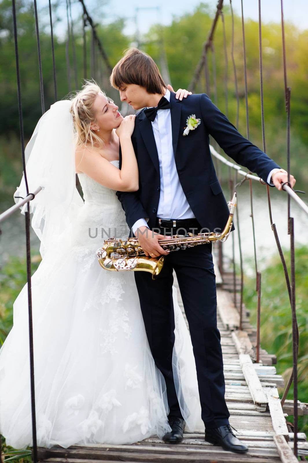 Bride and groom on the bridge with a saxophone by timonko