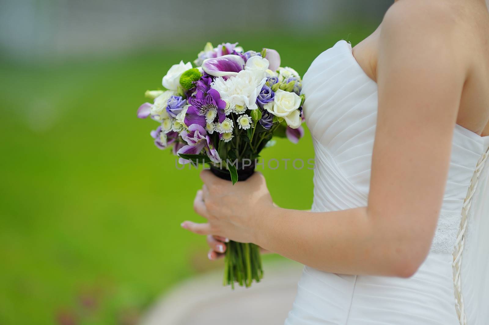 wedding bouquet in hands of the bride in profile purple flowers