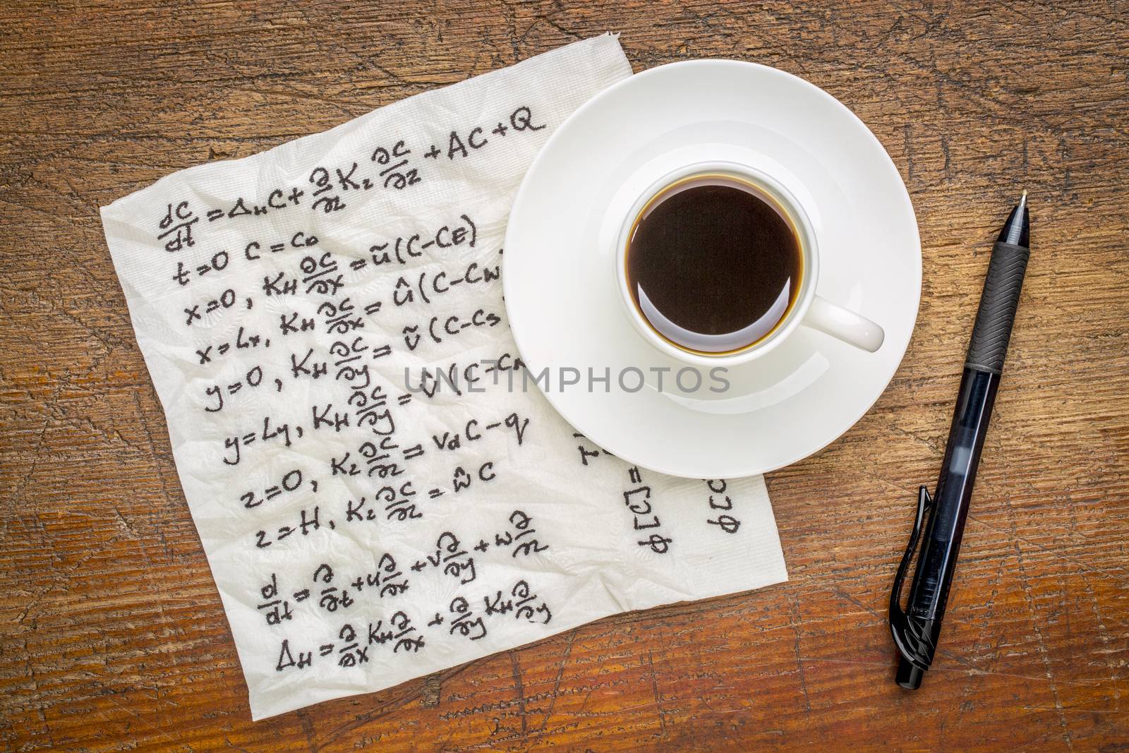 mathematical equations of physics - handwriting on a napkin with a cup of coffee on a rustic wooden table