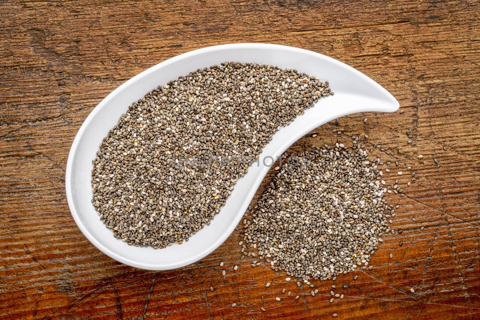 chia seeds in a teardrop shaped bowl - top view against rustic wood