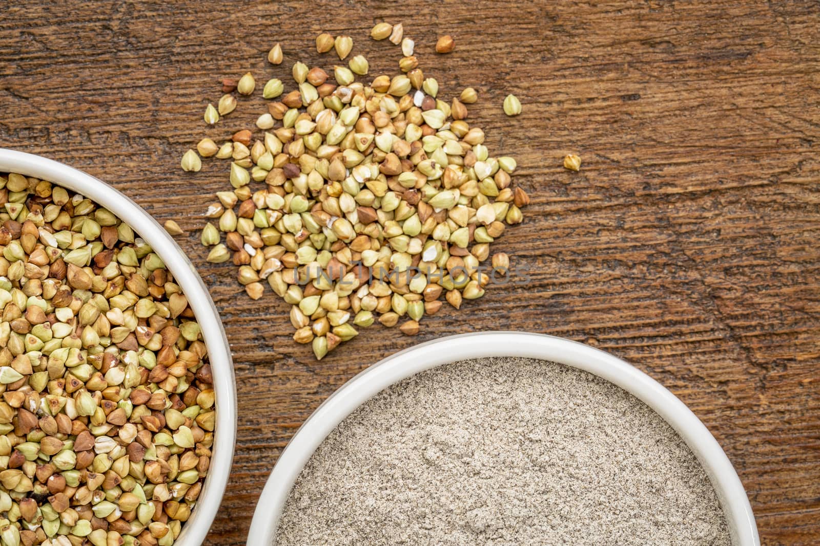 gluten free buckwheat grain and flour - top view of two ceramic bowls against rustic wood