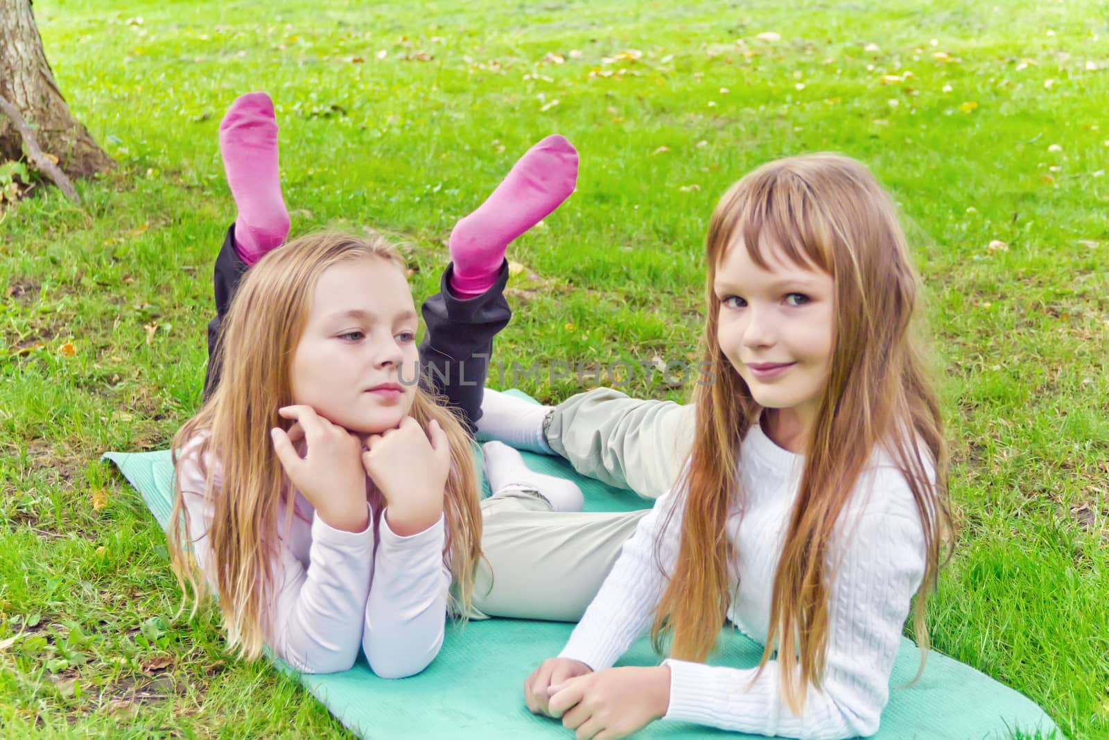 Photo of two girls sitting on grass in summer